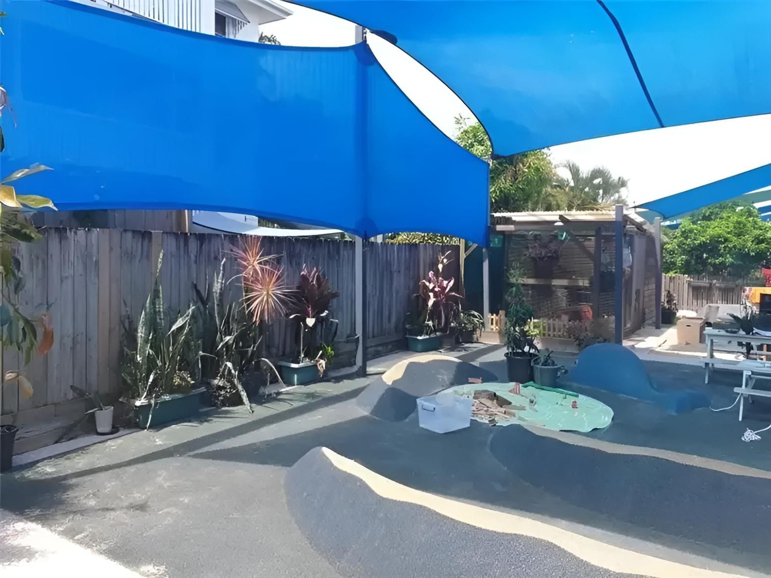 A Backyard With Blue Umbrellas and a Wooden Fence — Style Shades Installation In Ravenshoe, QLD