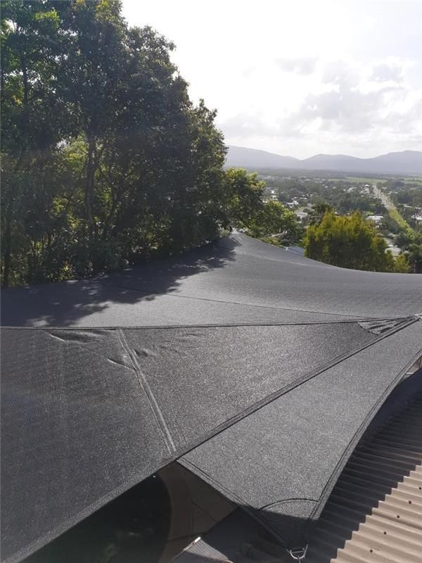 A Black Umbrella Is Sitting On Top Of A Roof With Trees — Style Shades Installation In Edmonton, QLD