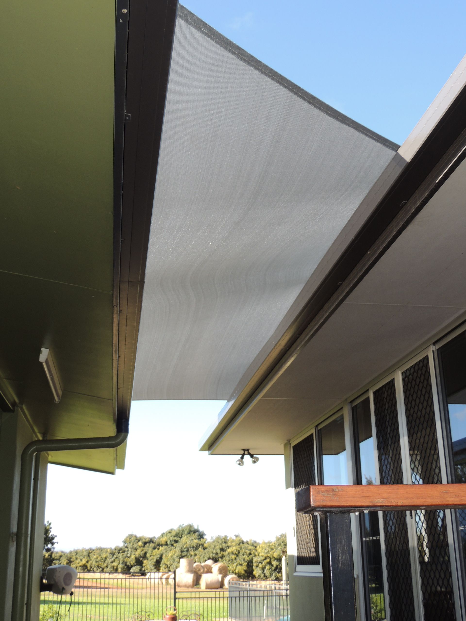 A White Awning Is Hanging From The Roof Of A Building — Style Shades Installation In Edmonton, QLD
