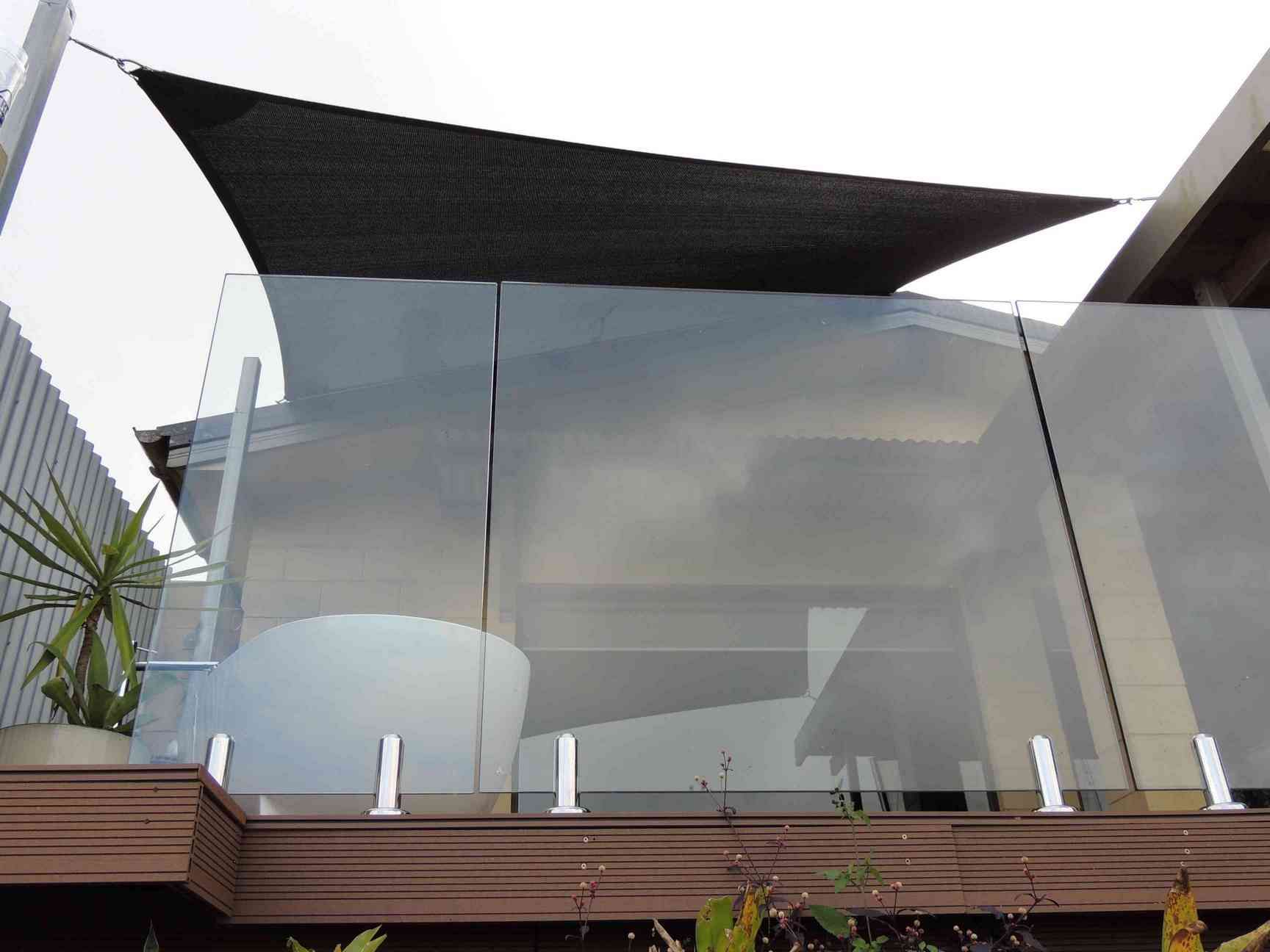 A Balcony With a Glass Railing and a Black Umbrella — Style Shades Installation In Cooktown, QLD