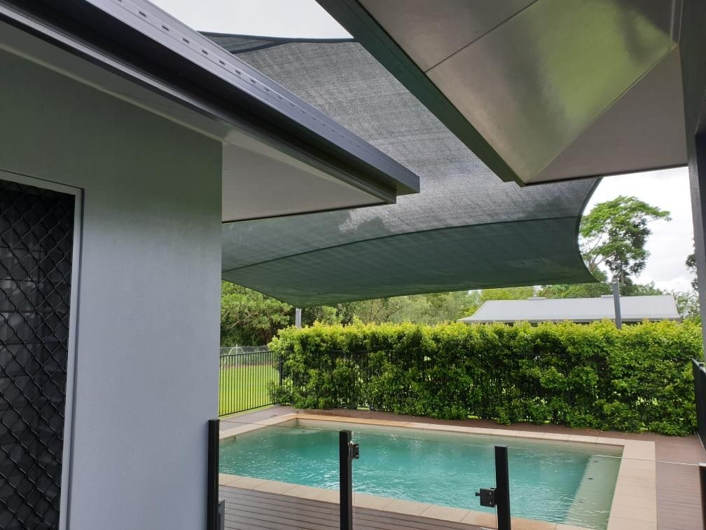 A Large Swimming Pool Is Covered By A Shade Sail — Style Shades Installation In Mareeba, QLD