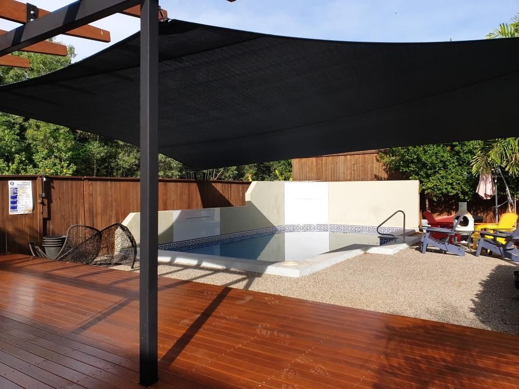 A Wooden Deck With A Swimming Pool In The Background — Style Shades Installation In Edmonton, QLD