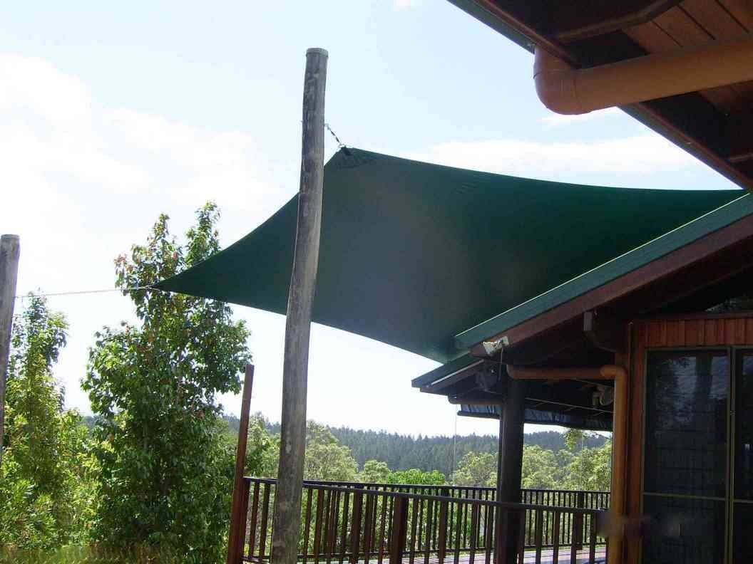 A Green Awning Is Hanging From The Roof Of A House — Style Shades Installation In Edmonton, QLD