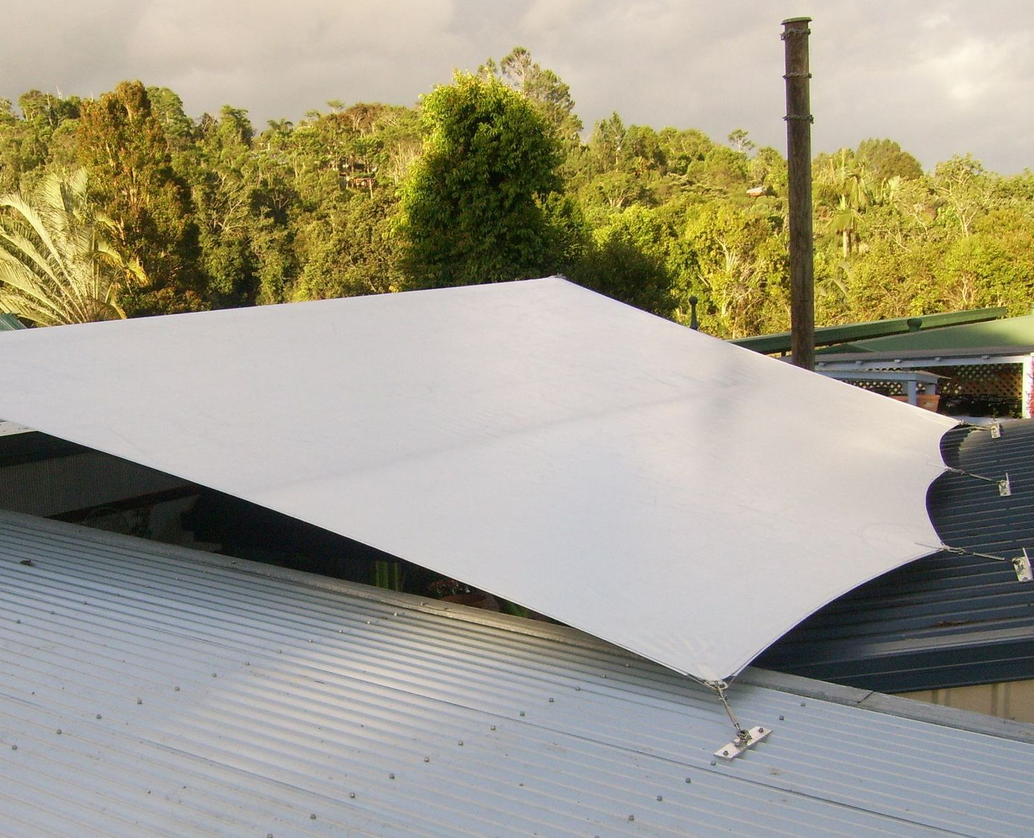 A Roof With a White Tarp on It and Trees in the Background — Style Shades Installation In Smithfield, NSW