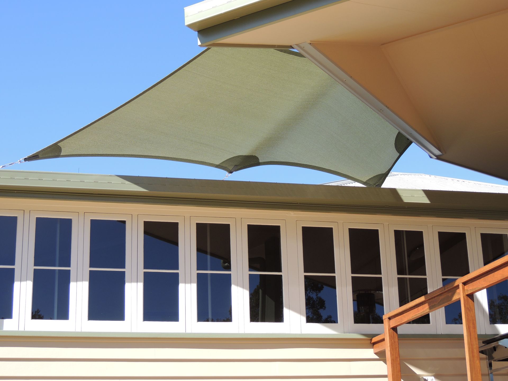 A Green Umbrella Is Hanging From The Roof Of A House — Style Shades Installation In Edmonton, QLD