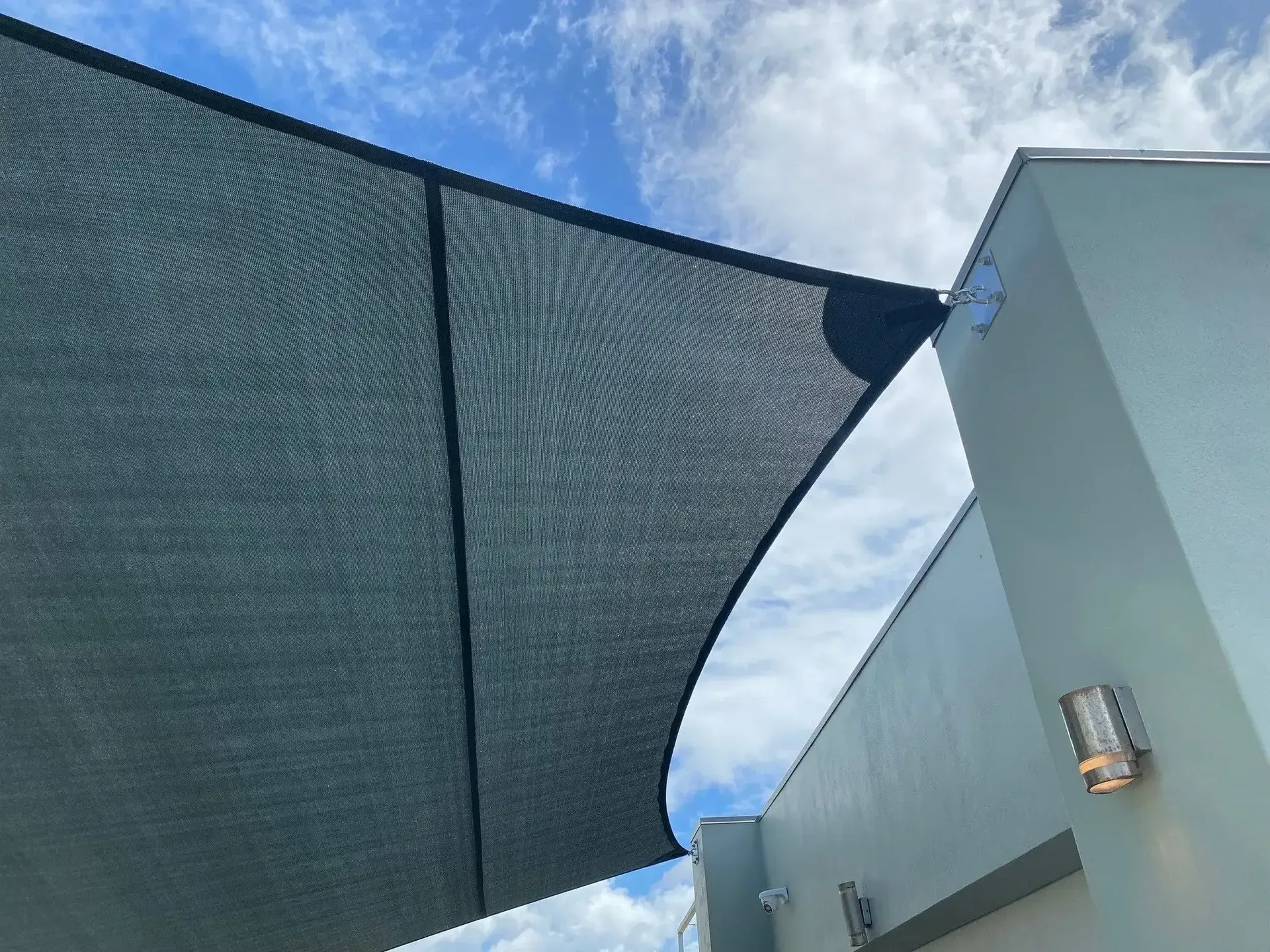 A Large Gray Umbrella Is Hanging From The Side Of A Building — Style Shades Installation In Atherton Tablelands, QLD