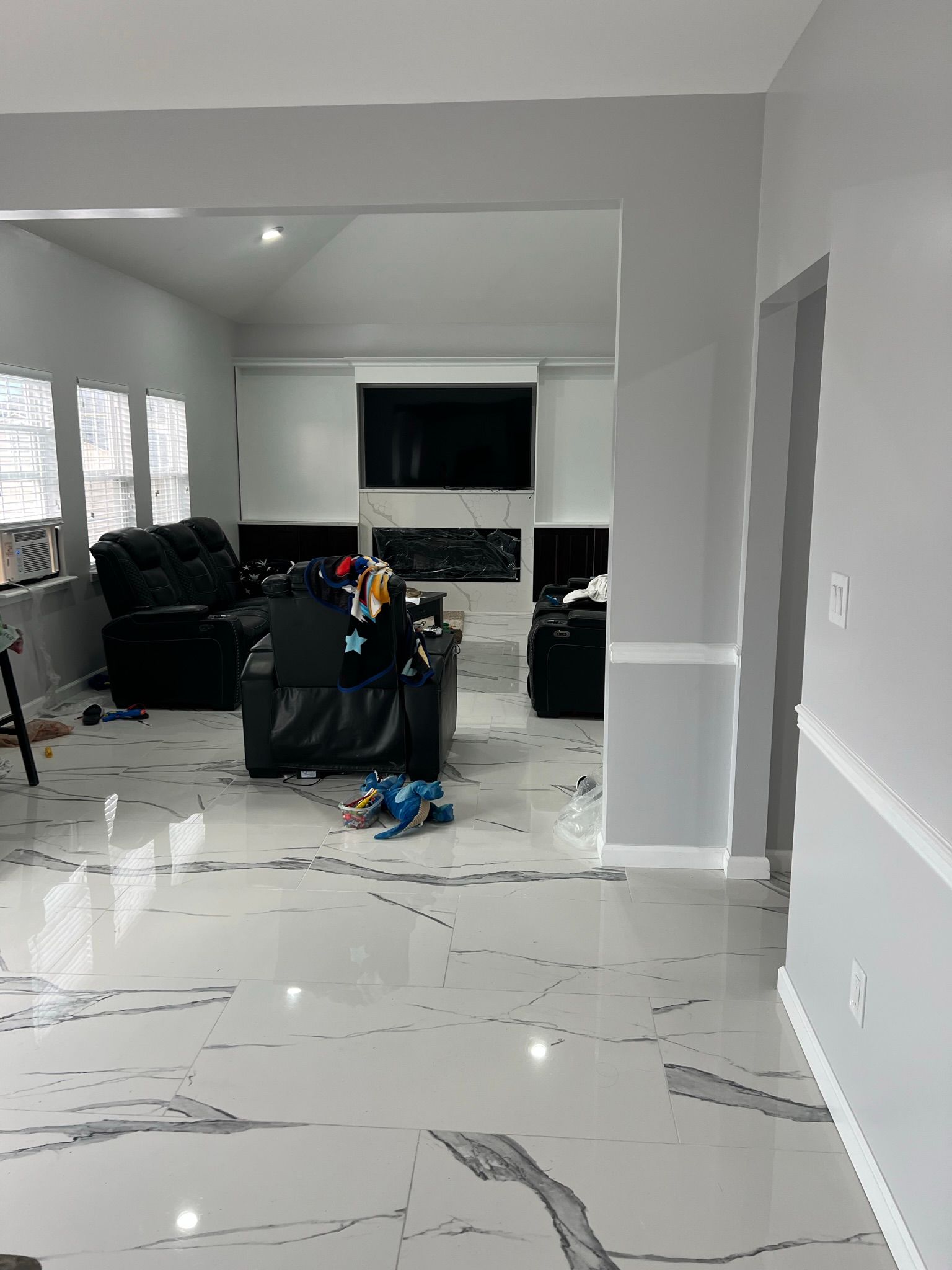 A living room with a marble floor and a fireplace.