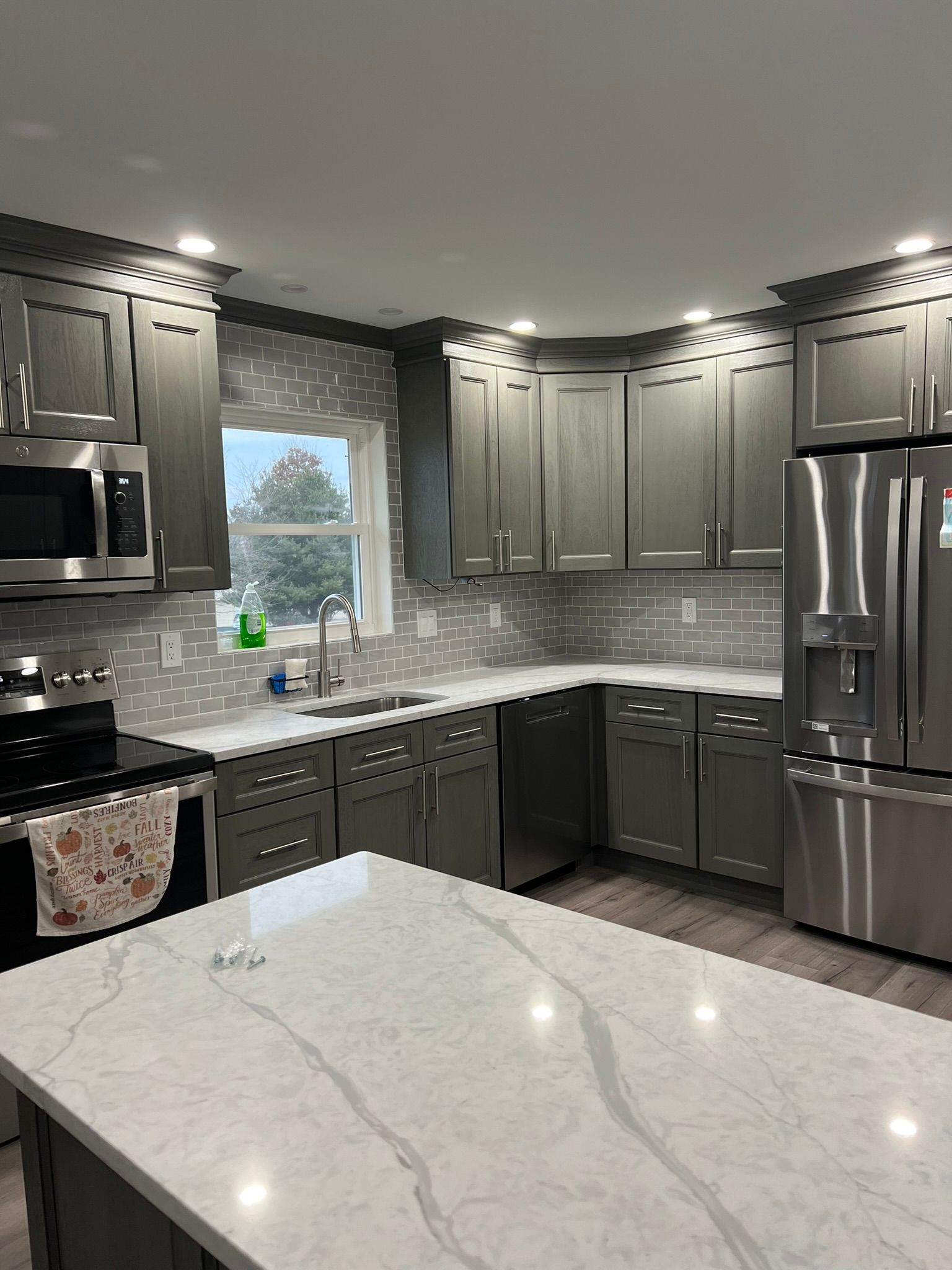 A kitchen with gray cabinets and stainless steel appliances