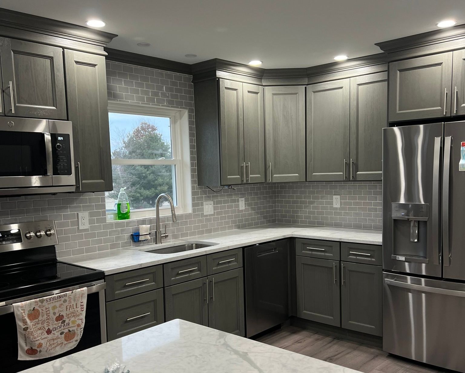 A kitchen with gray cabinets and stainless steel appliances.