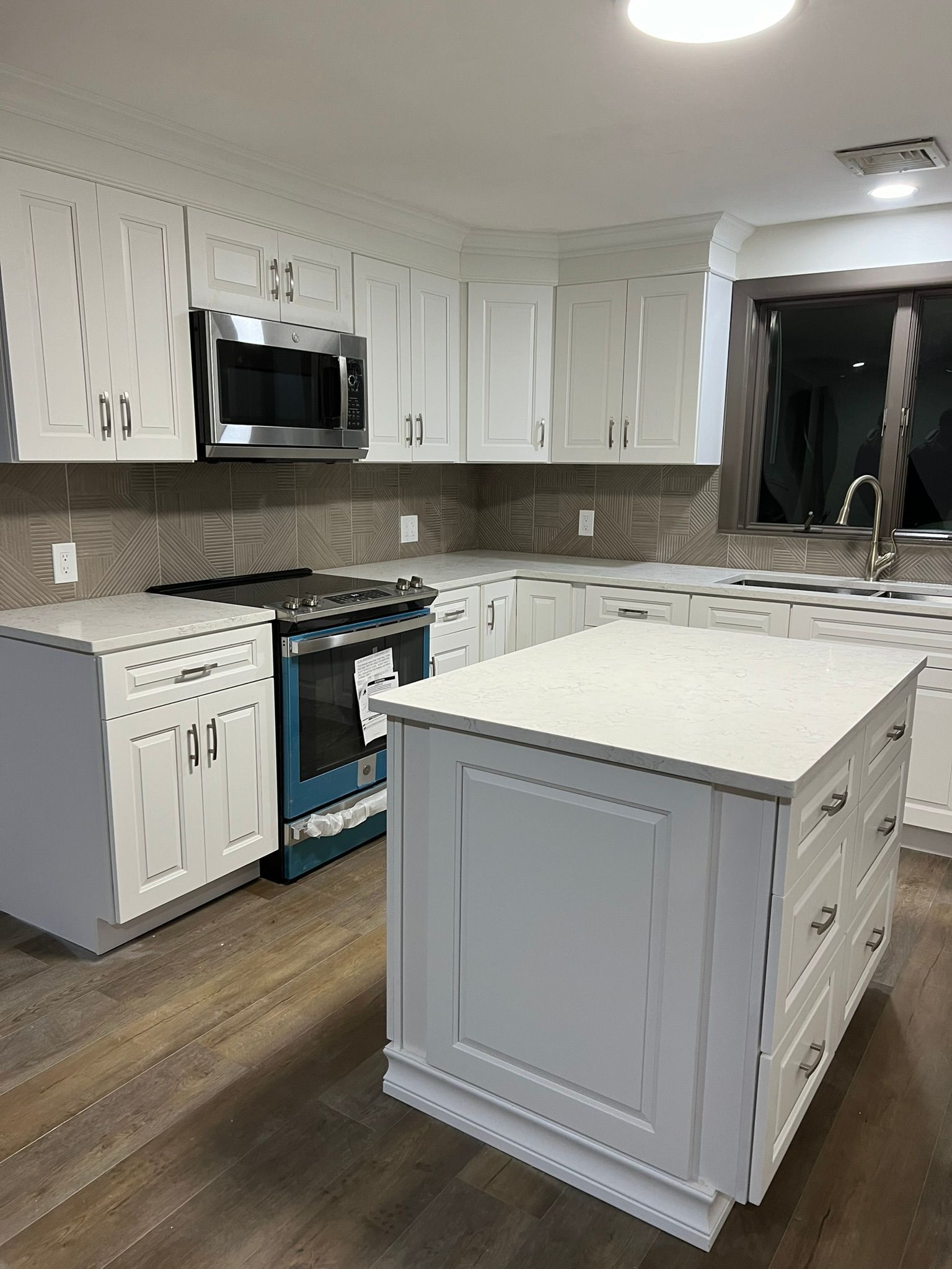 A kitchen with white cabinets and a large island in the middle.