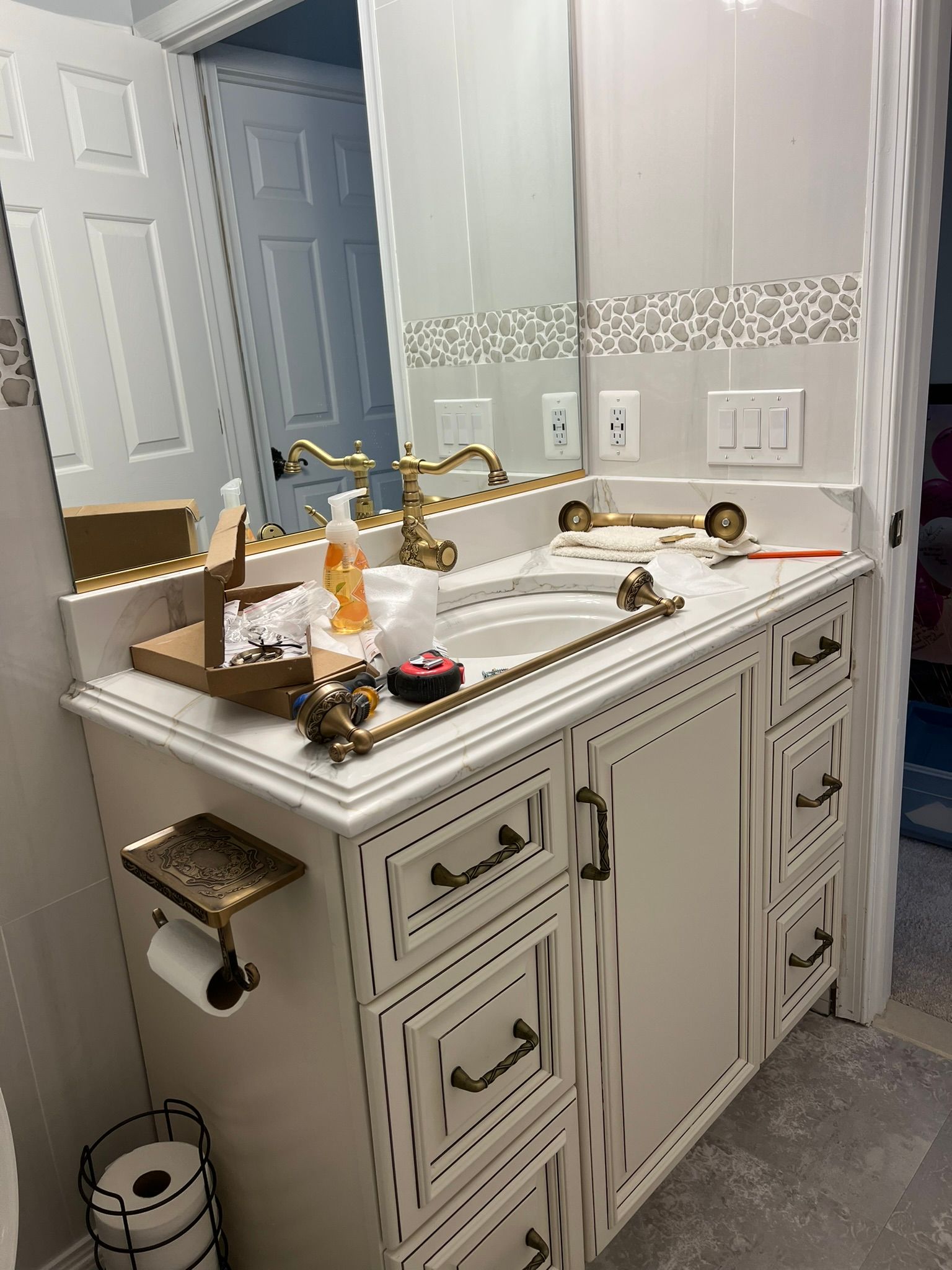 A bathroom with two sinks , a mirror , and a toilet paper holder.
