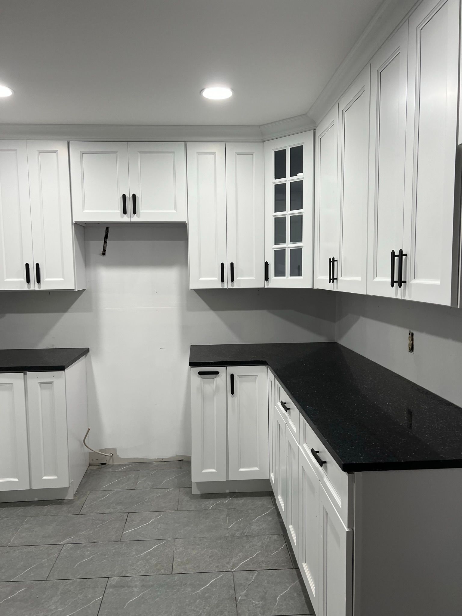 A kitchen with white cabinets and black counter tops