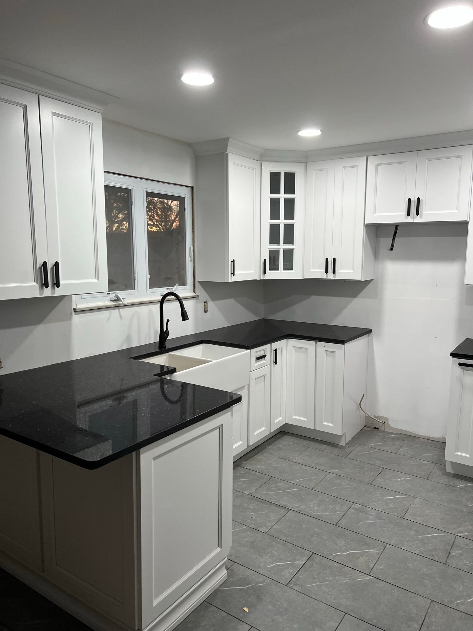 A kitchen with white cabinets and black counter tops