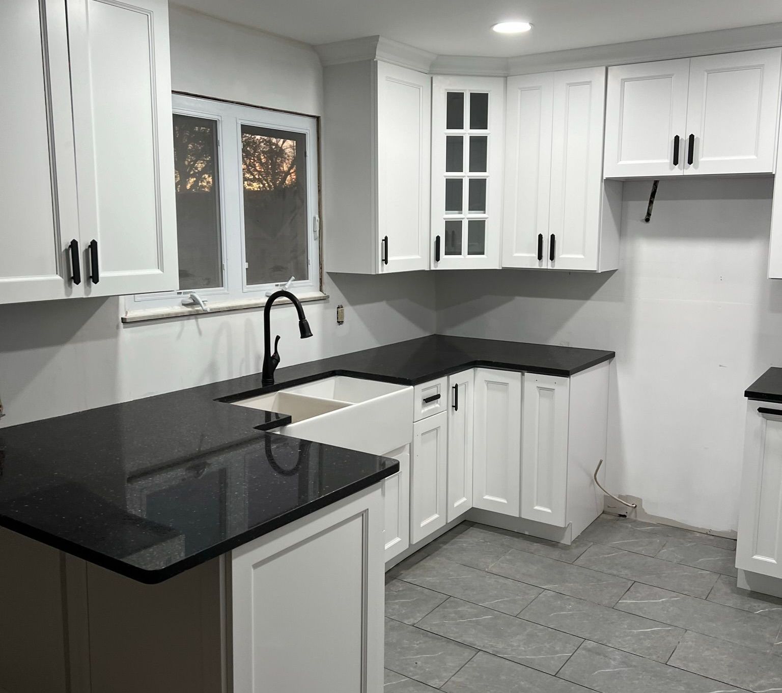 A kitchen with white cabinets and black counter tops