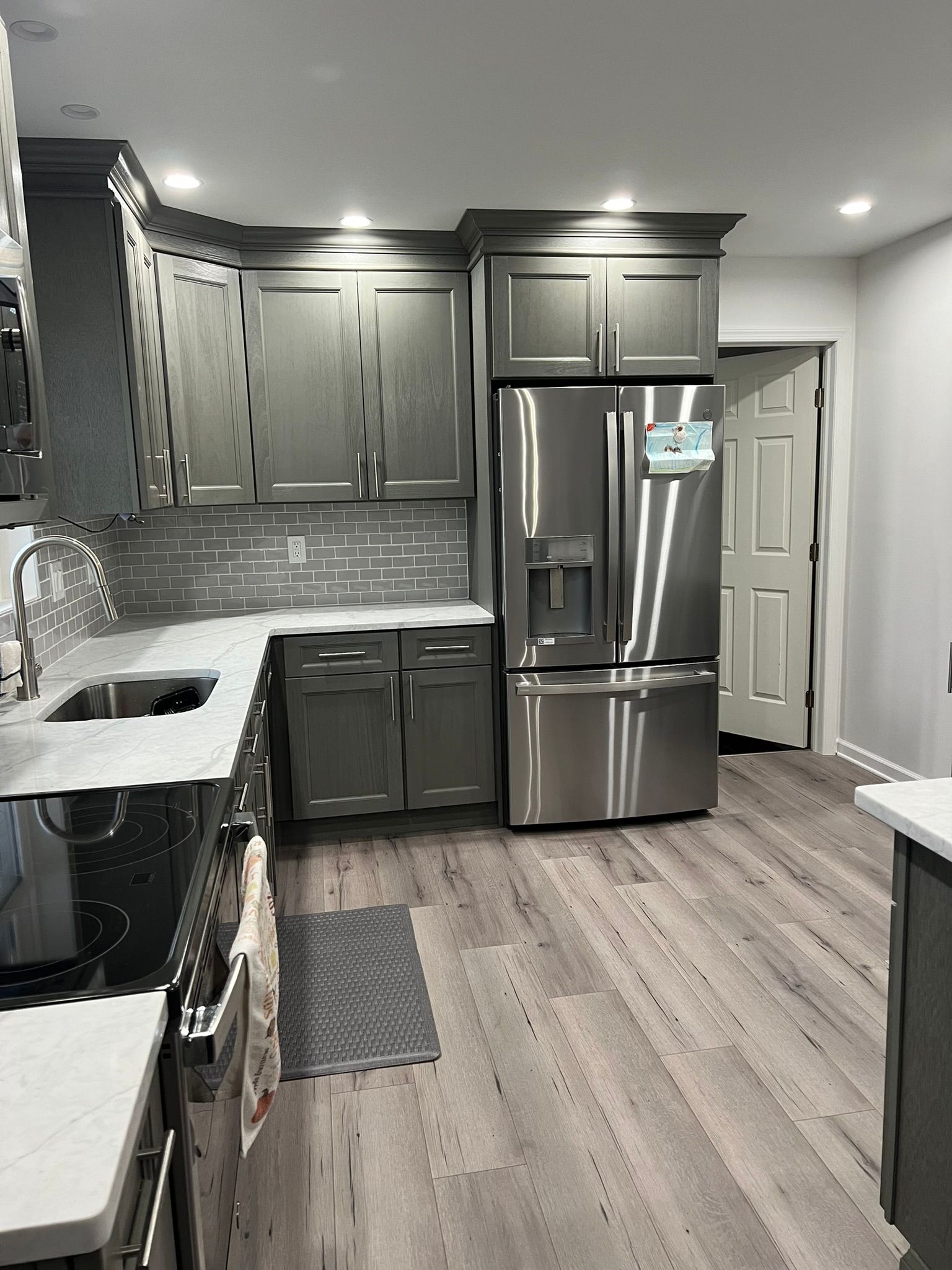 A kitchen with stainless steel appliances and gray cabinets.
