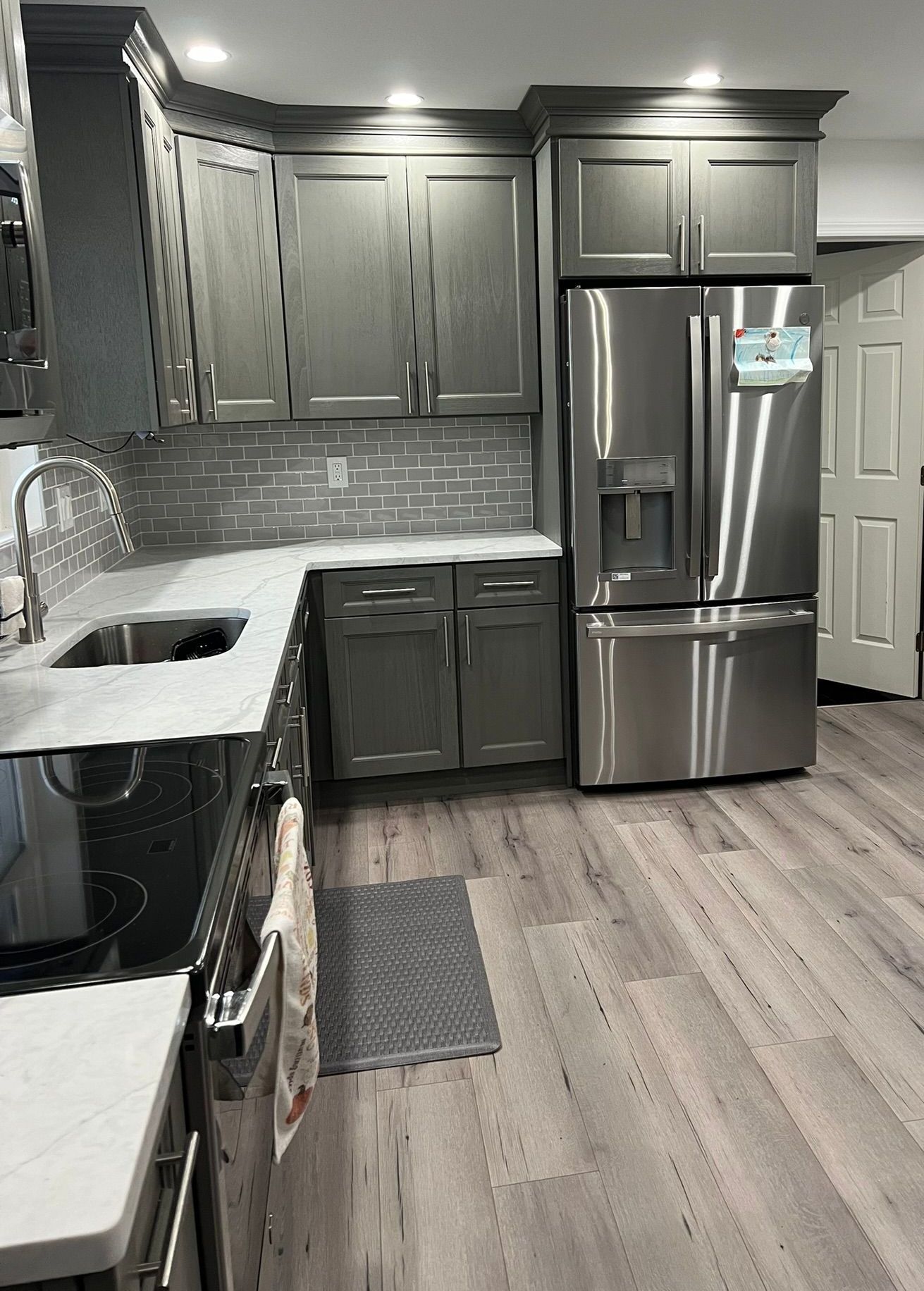 A kitchen with stainless steel appliances and gray cabinets.