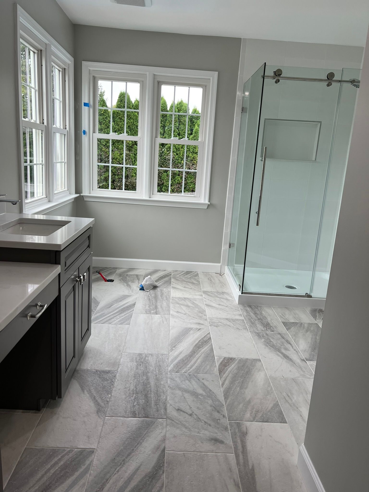 A bathroom with a sink , shower , and window.