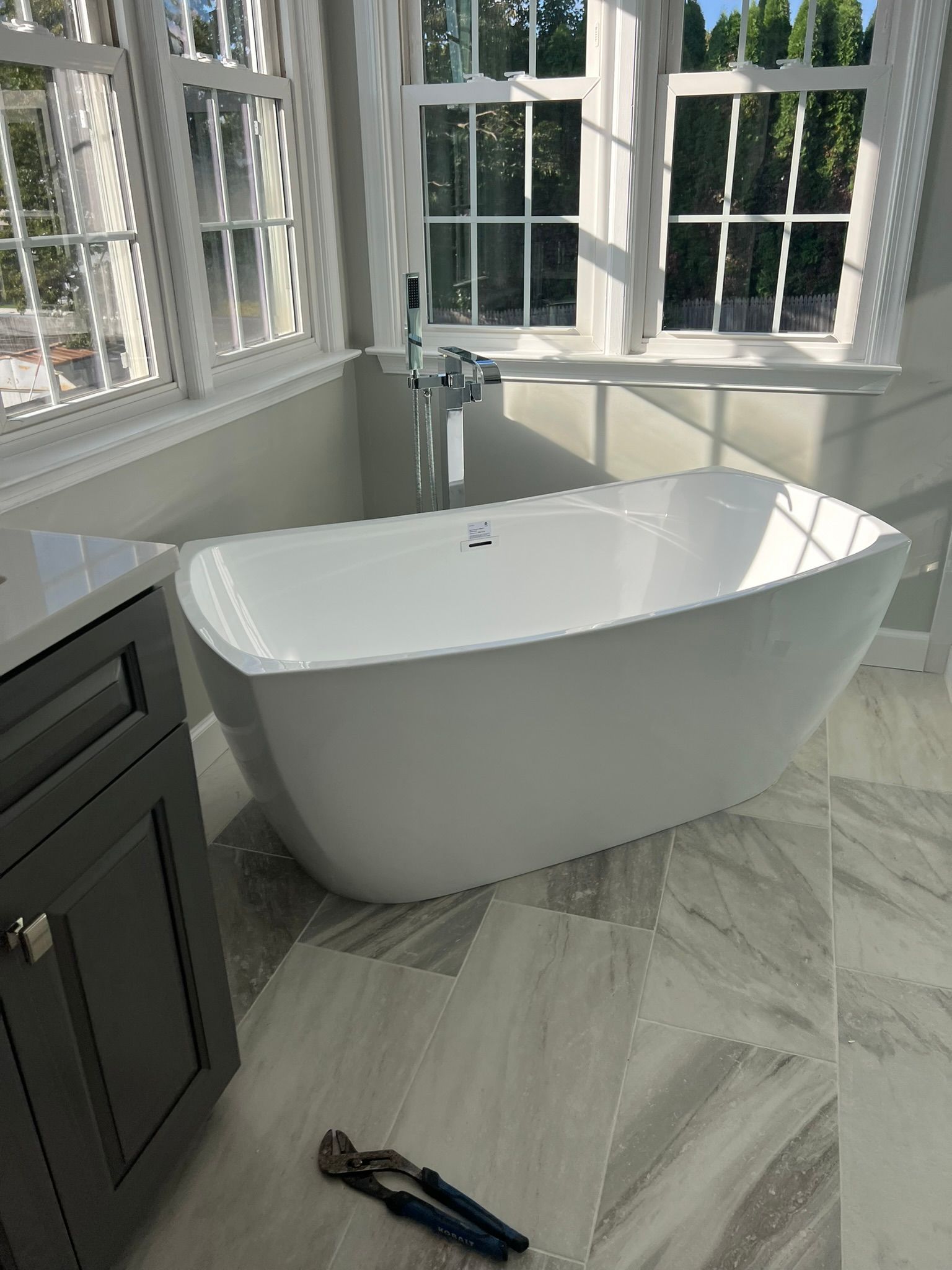 A white bathtub is sitting in a bathroom next to a window.