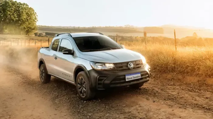 SUV vermelho estacionado em paralelepípedos com o pôr do sol ao fundo.