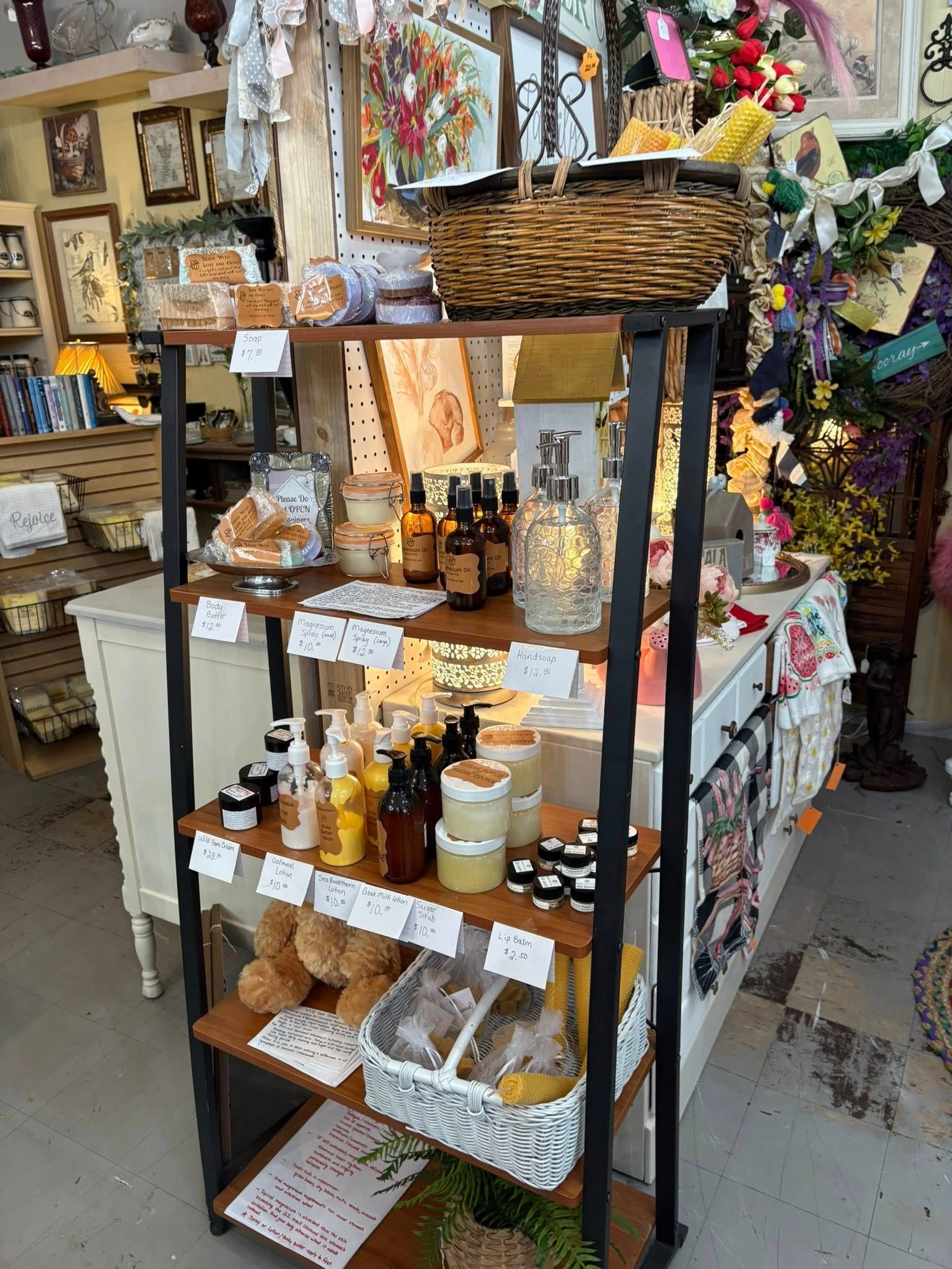 Gift shop display of candles, jars, and soaps on a black shelving unit with a wicker basket on top.