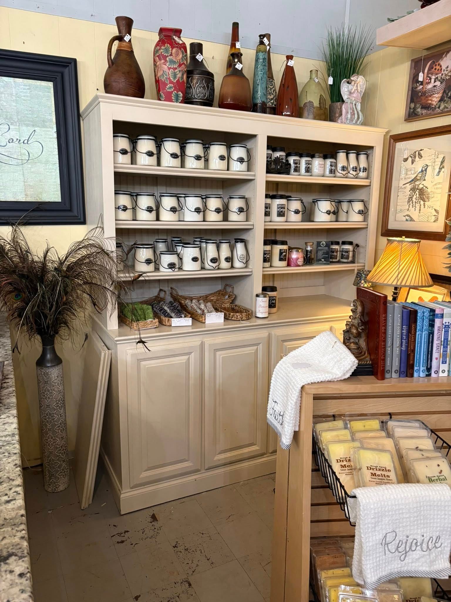 Antique cabinet with shelves of mugs and decor in a cozy shop corner, beside a lamp and display table.