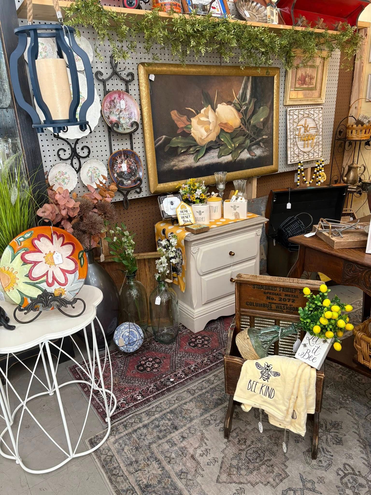 Decorative vintage corner with floral art, white furniture, plants, and patterned rugs