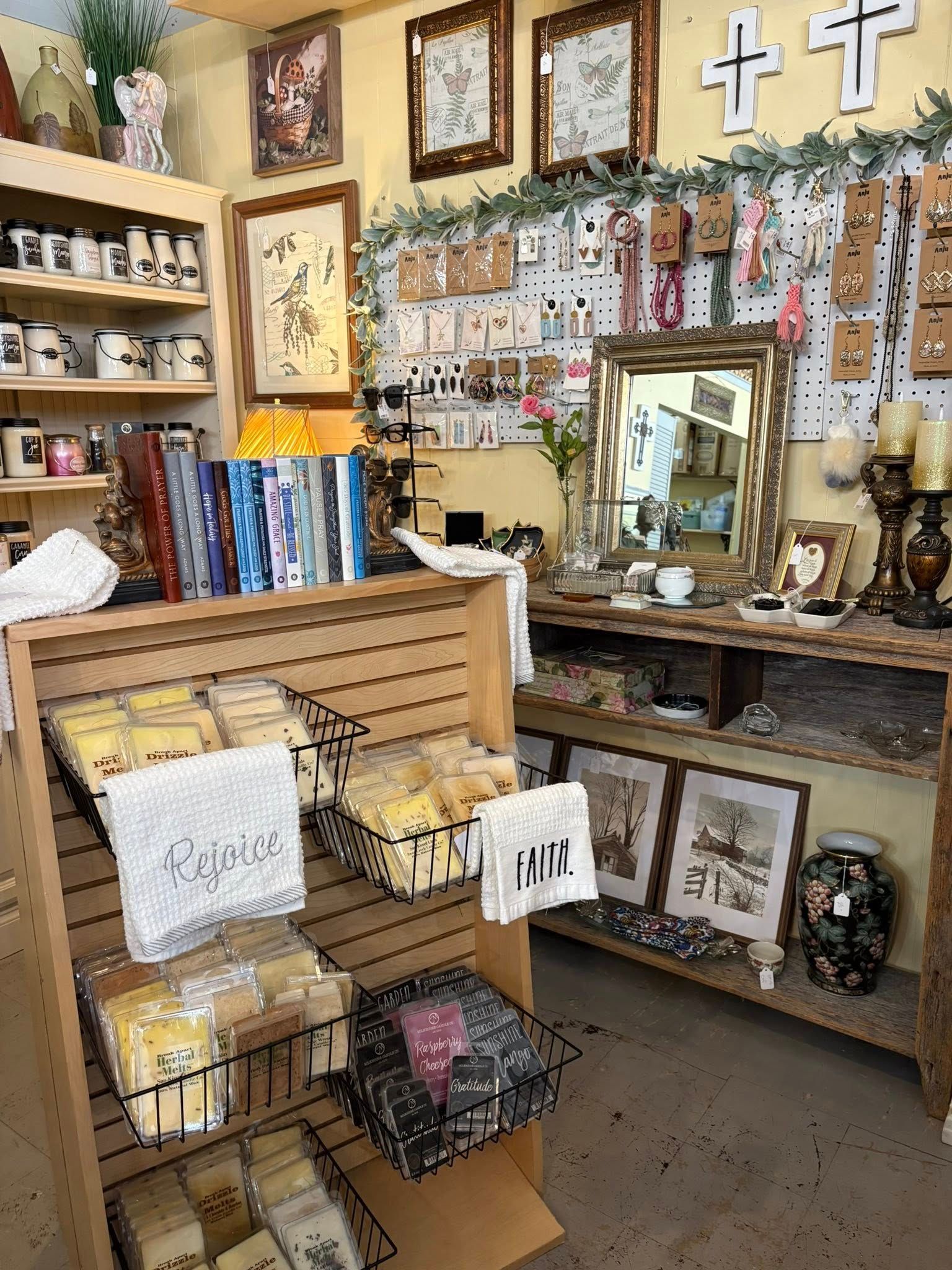 Small gift shop display with crosses, framed art, candles, and religious décor on shelves and walls