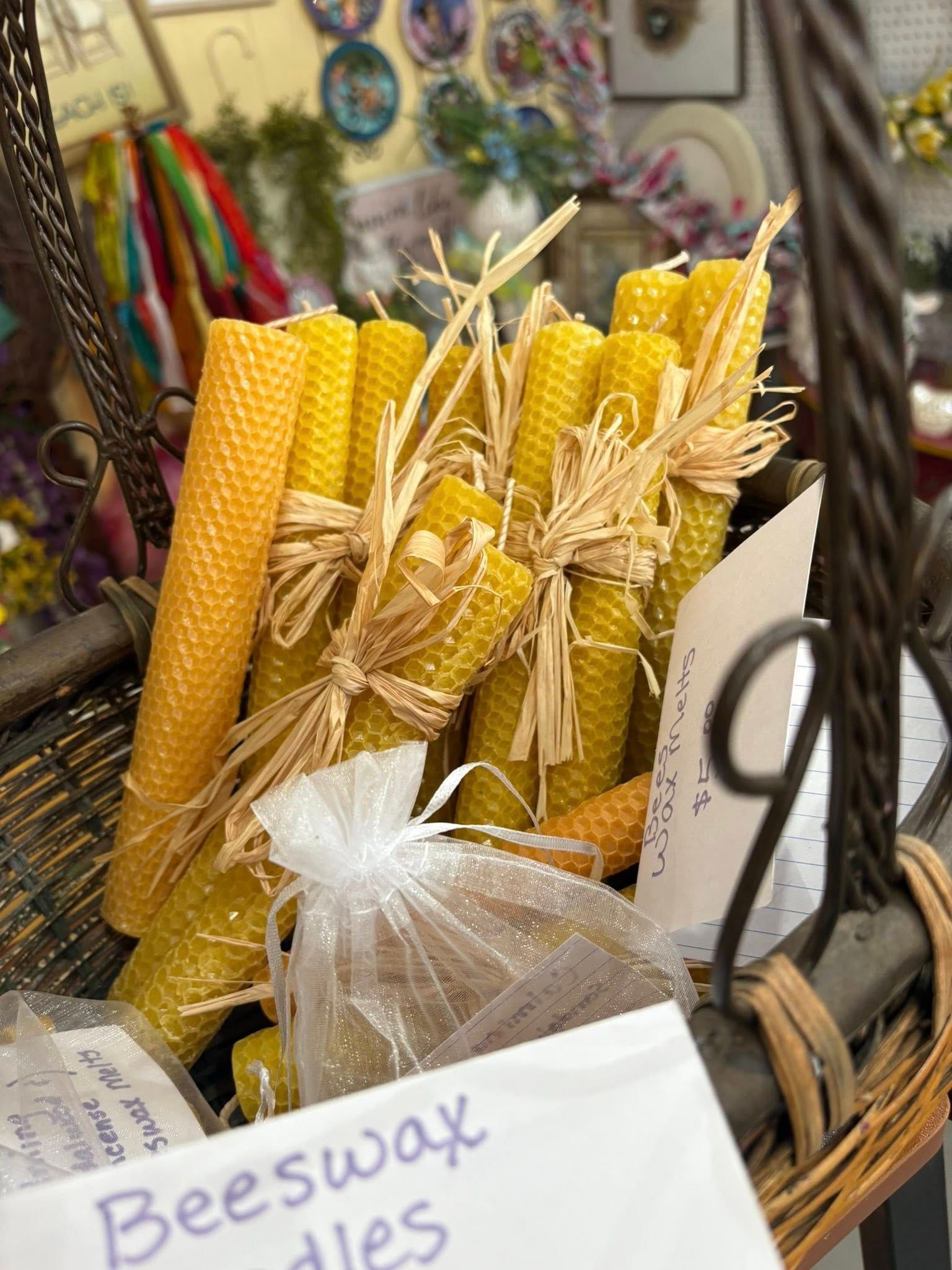 Beeswax candles in a basket at a craft market, with a sign reading “Beeswax”