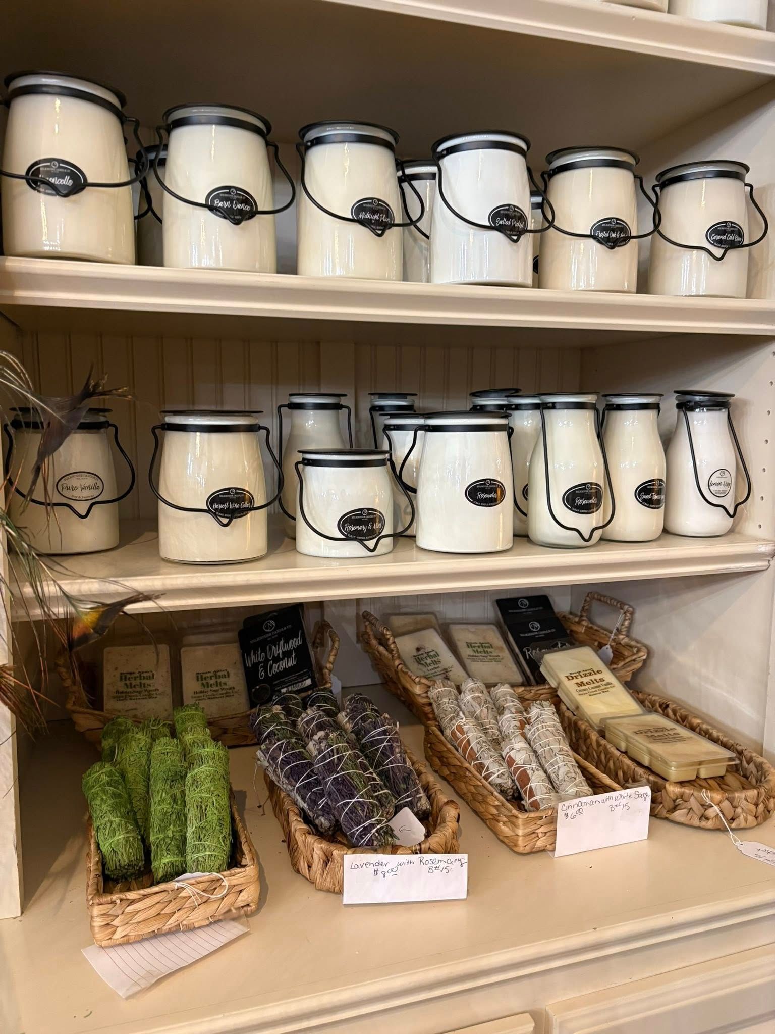 Shelved display of white jars with black labels and packaged herbs or tea bags on a wooden counter