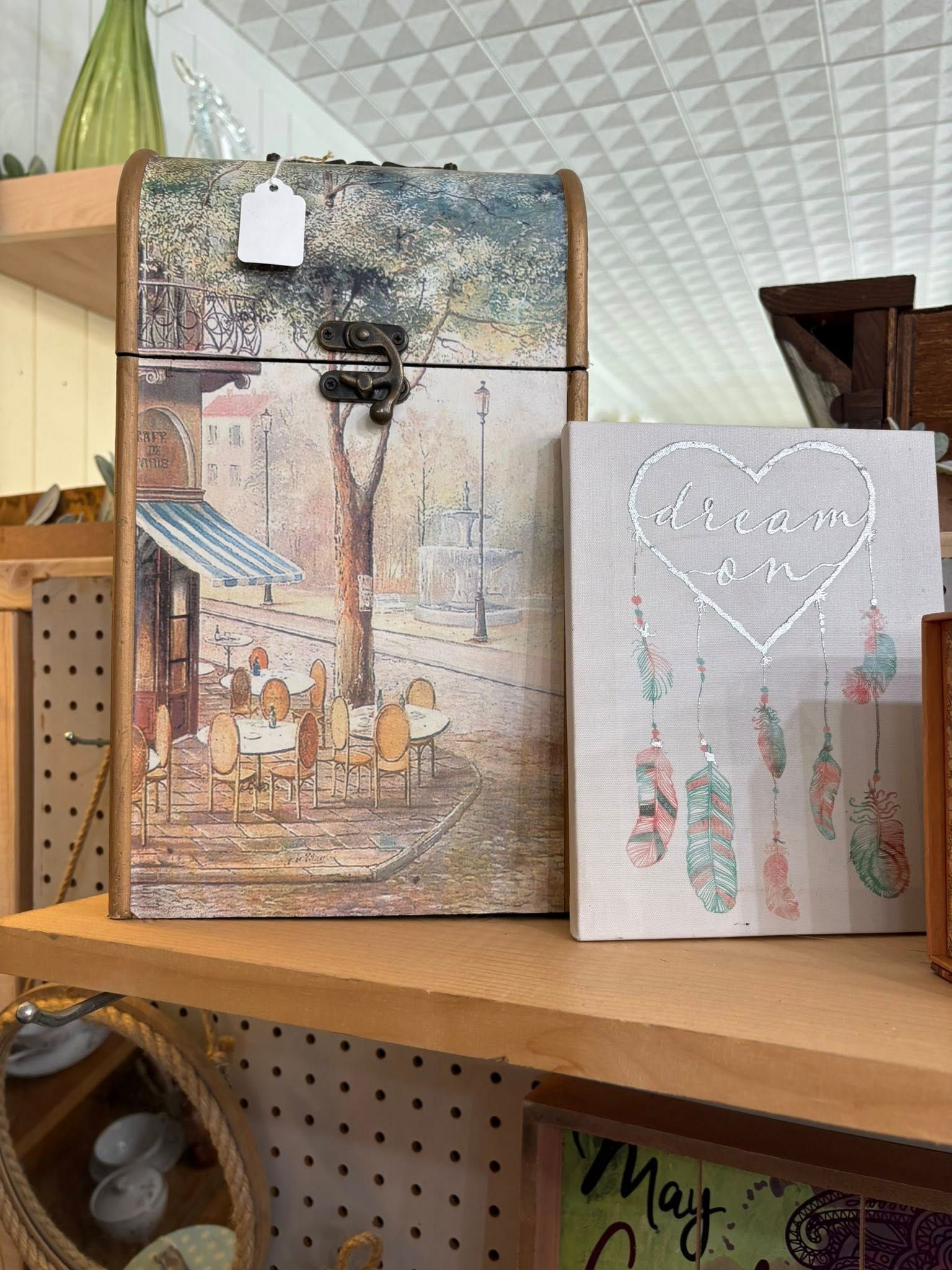 Decorative gift boxes on a wooden shelf, including a tall textured box and a smaller silver box with hanging ornaments.