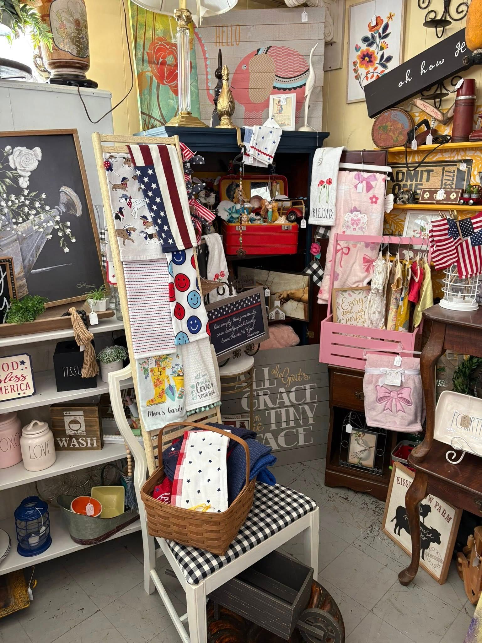 Cluttered craft shop display with handmade cards, signs, baskets, and colorful decorations.