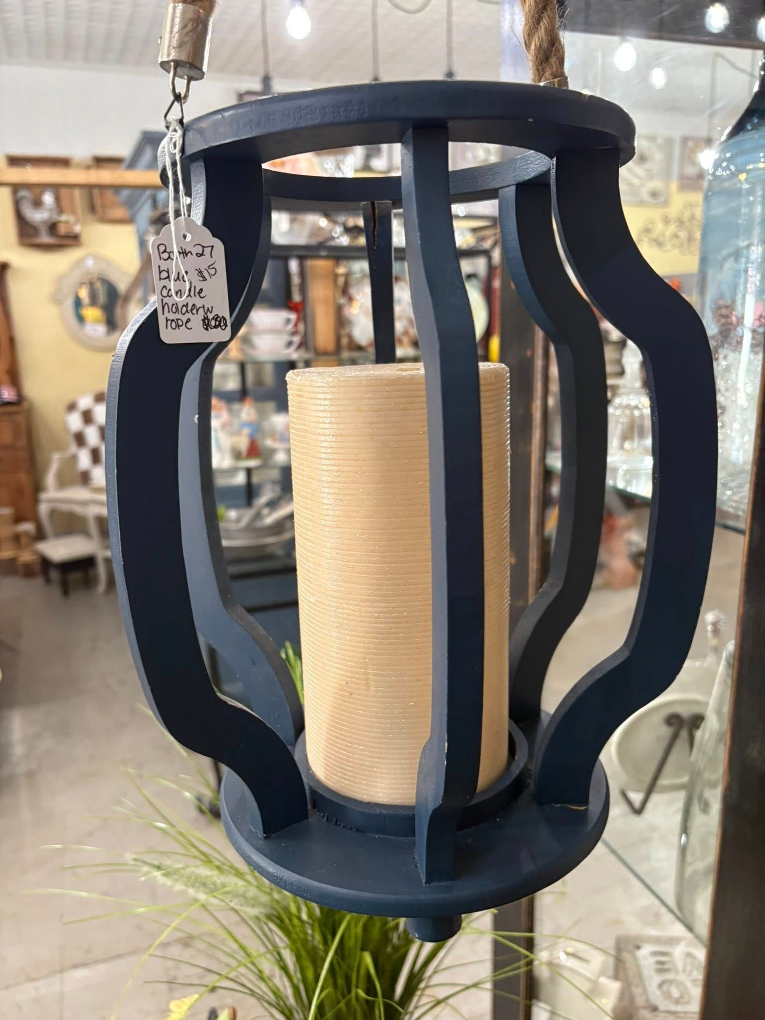 Black metal lantern-style pendant light with a rope-wrapped center hanging in a shop display