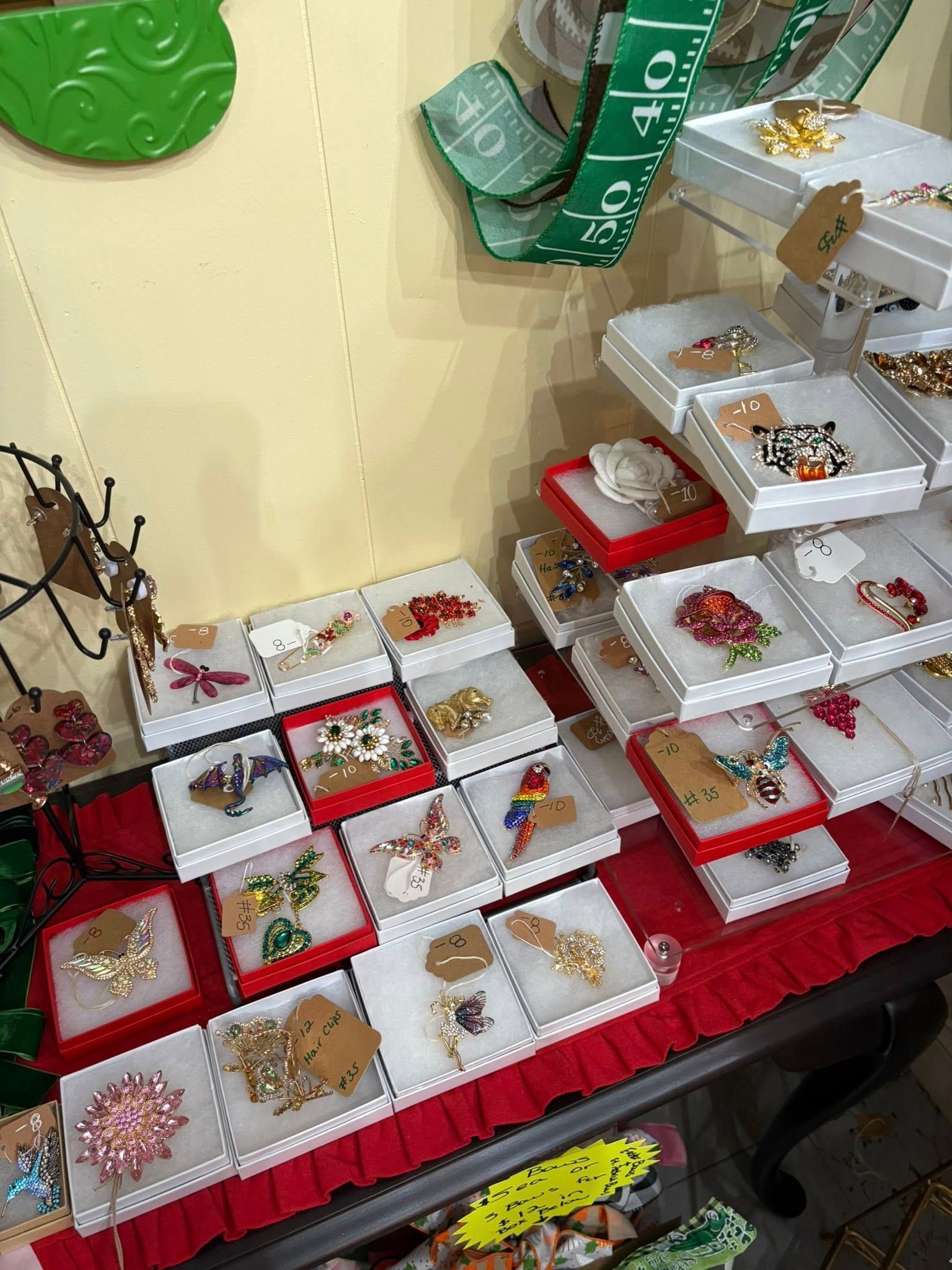 Red-and-white jewelry display with bracelets, rings, and necklaces arranged on tiered trays and tables