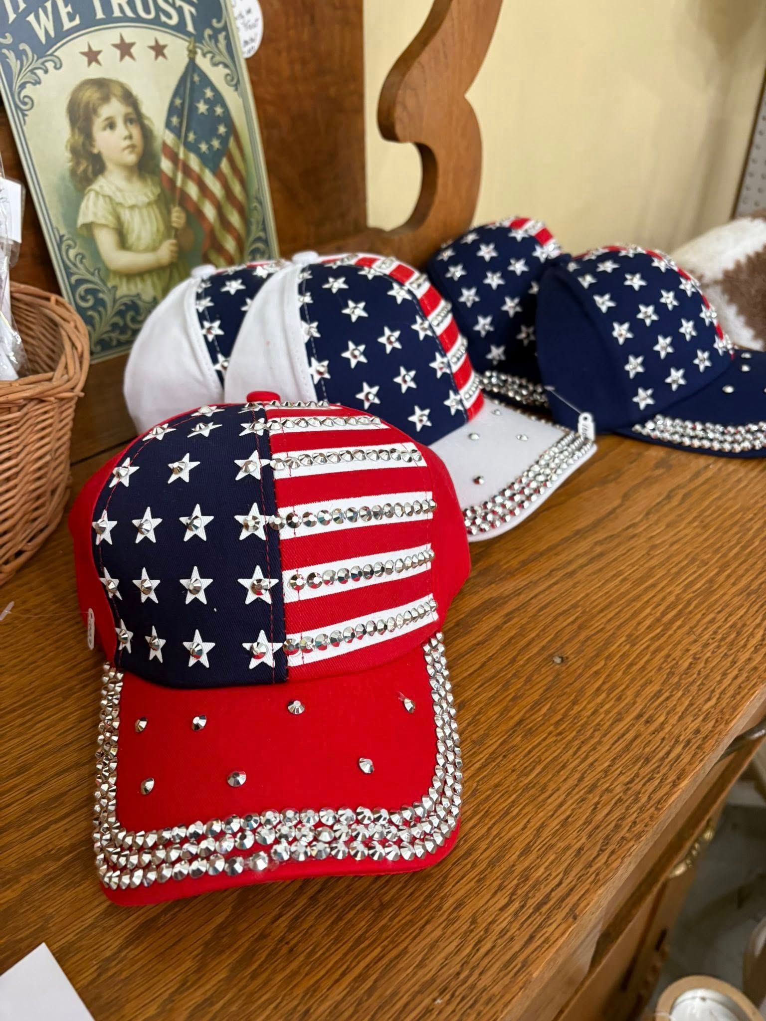 Red, white, and blue star-spangled baseball caps on a woven table display.