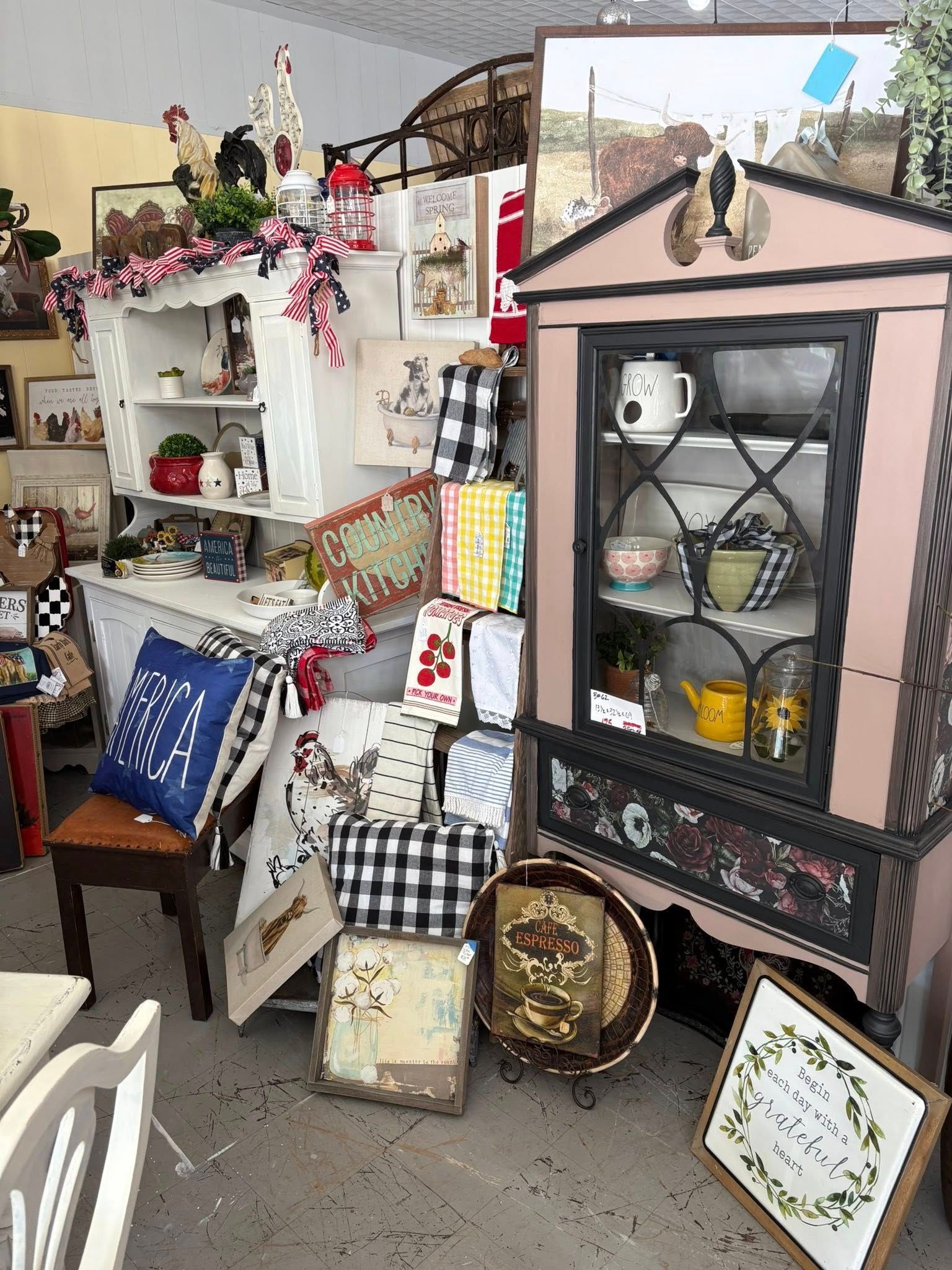 Eclectic display of vintage decor, shelves, framed art, and patterned chairs in a cozy shop corner