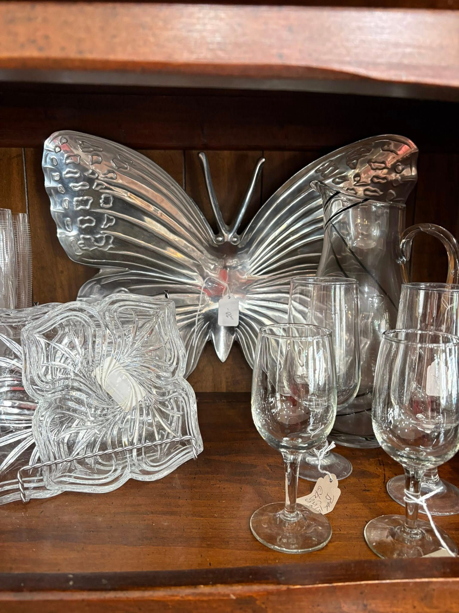 Glass butterfly figurine displayed with cut-glass bowls and champagne flutes on a shelf