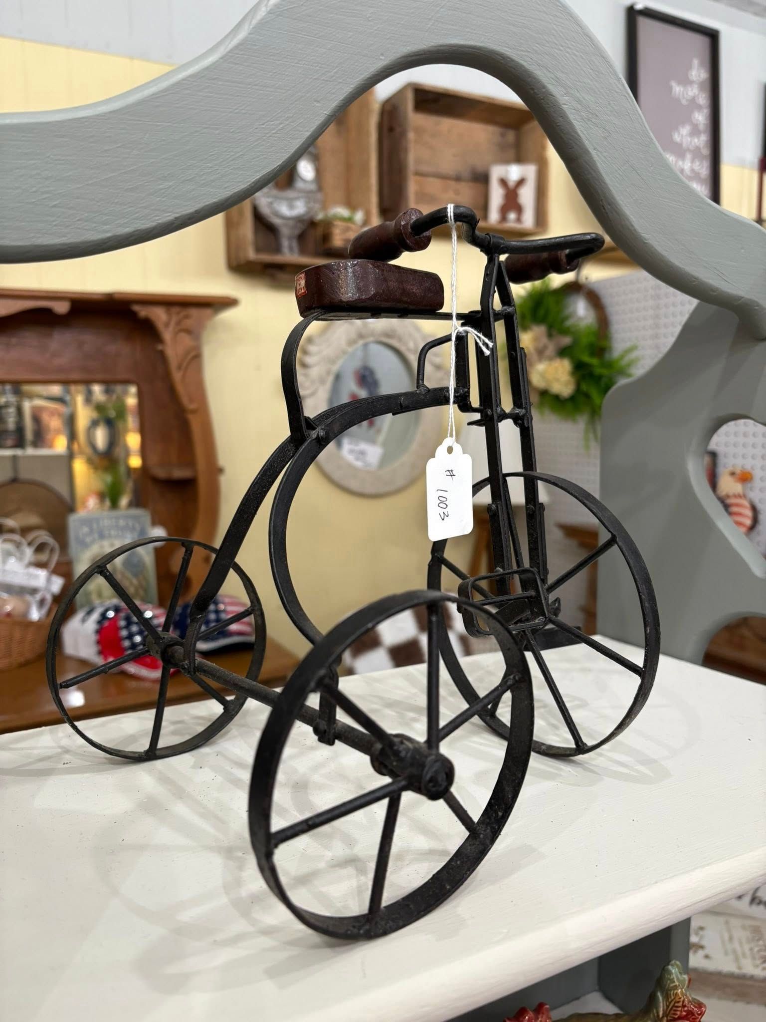 Black vintage-style bicycle sculpture with a tag on a white tabletop in a home interior