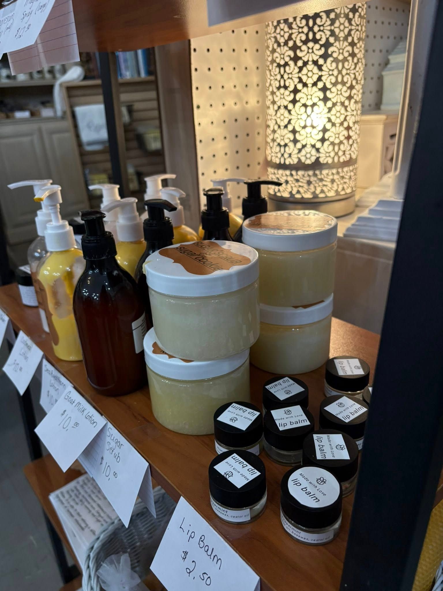 Display of assorted bottles, jars, and small containers on a wooden counter in a shop.