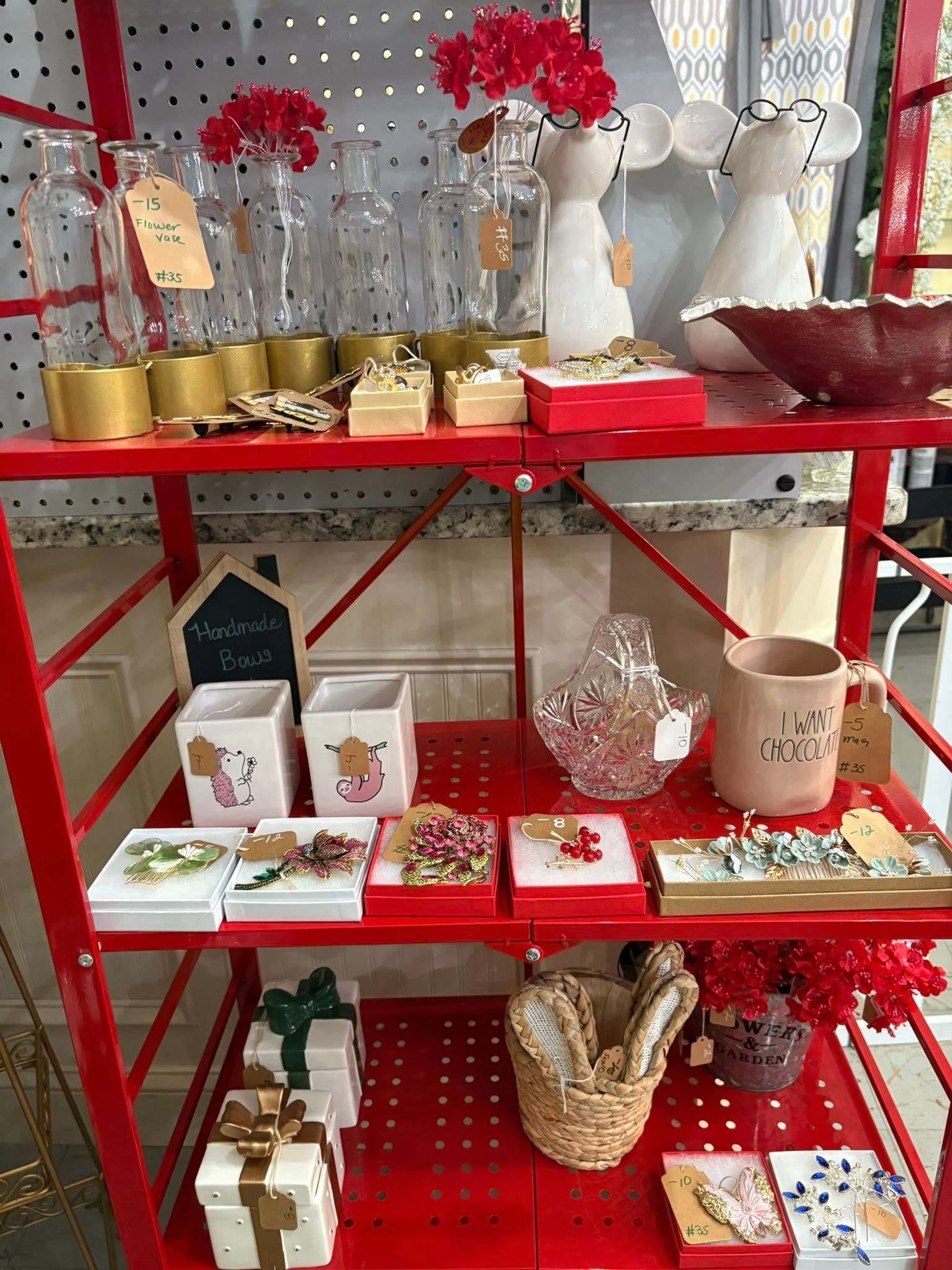 Red display shelf with white and gold decorative gift items and flowers in a store-like setting