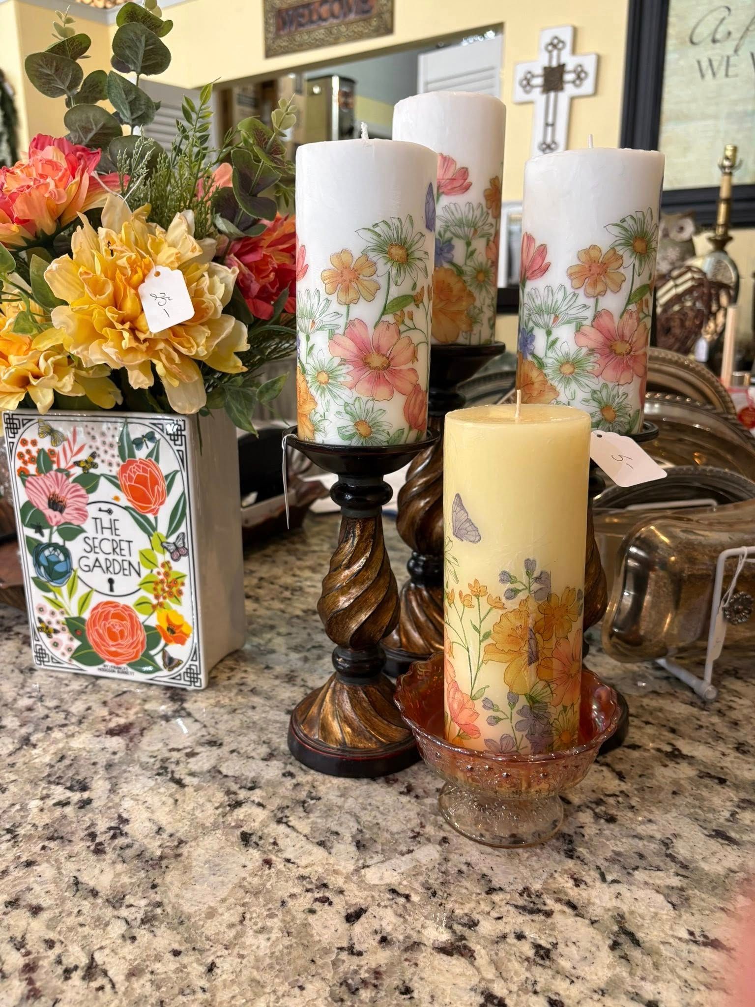 Floral candles and fall decor arranged on a granite countertop with a framed floral card and bouquet