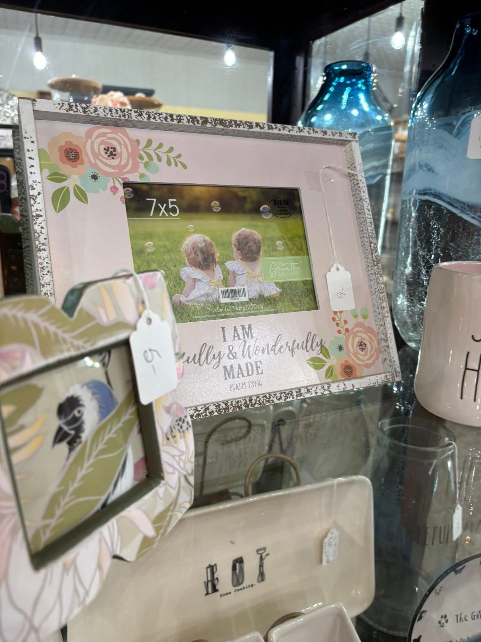 Decorative photo frame with floral accents on a shelf, showing two children outdoors.