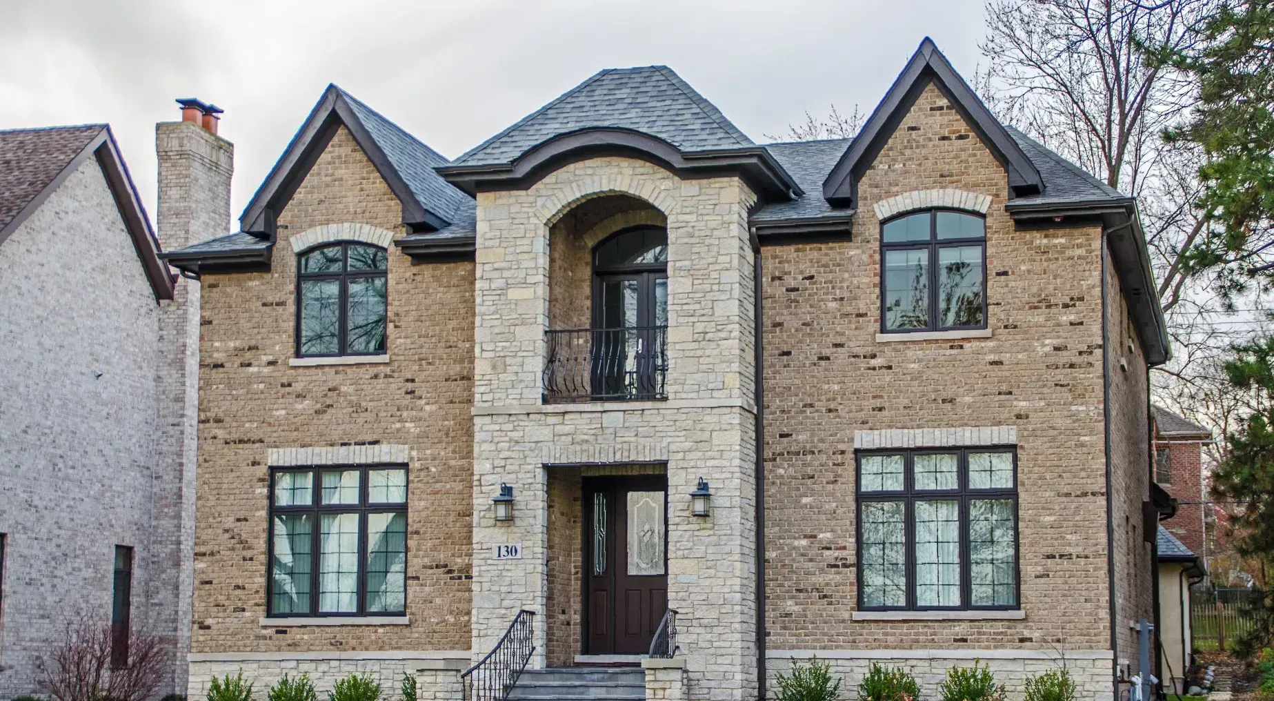 A large brick house with black windows and a black roof.