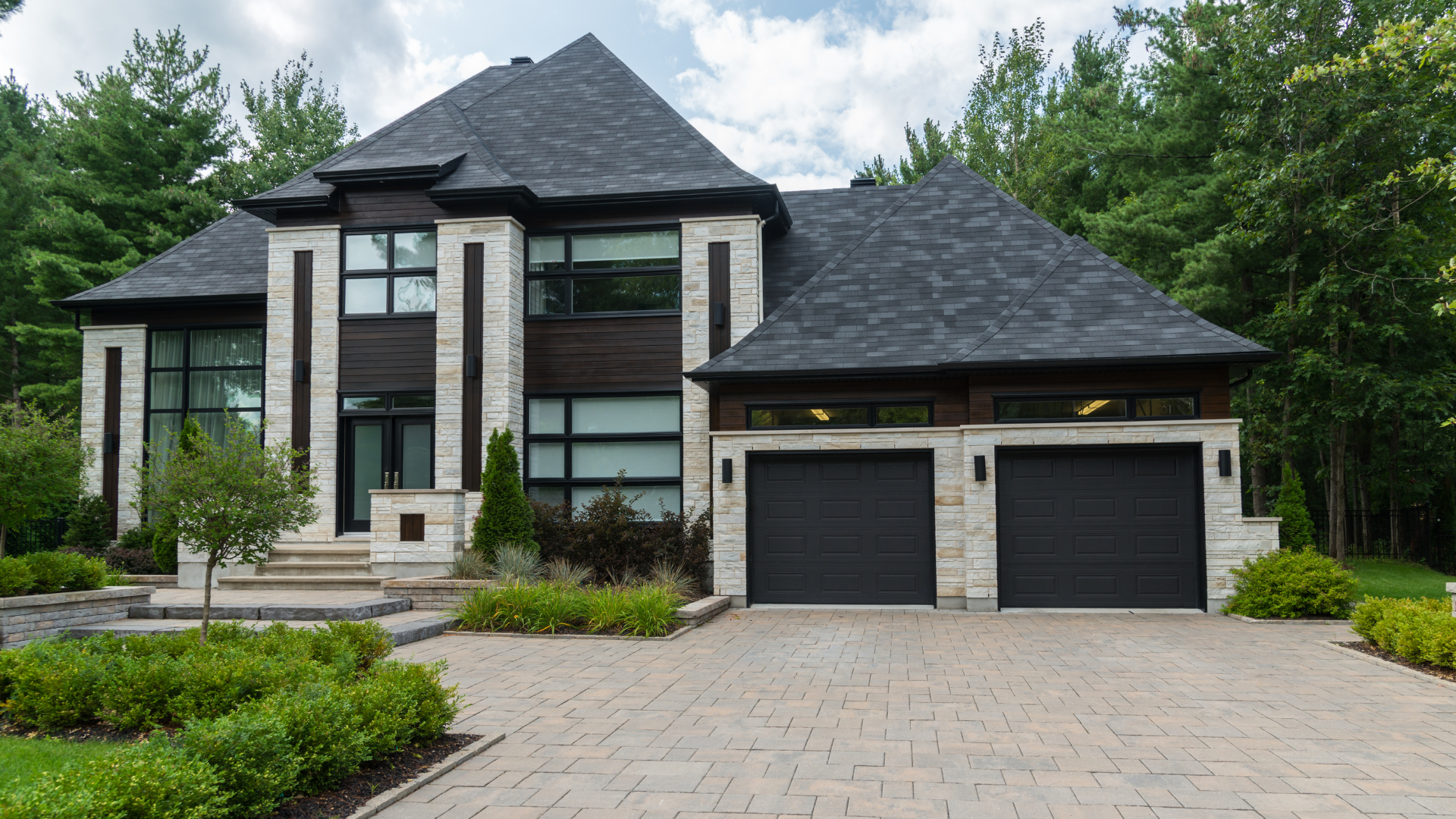 A large white house with a black roof and two black garage doors.