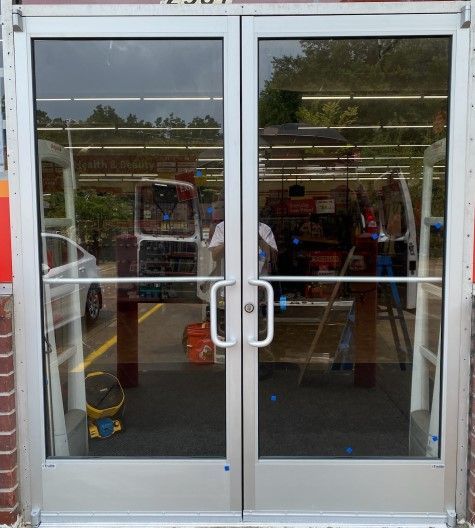 Double glass doors with silver frames, reflecting a store interior and exterior. Double glass doors with silver frames, reflecting a store interior and exterior.