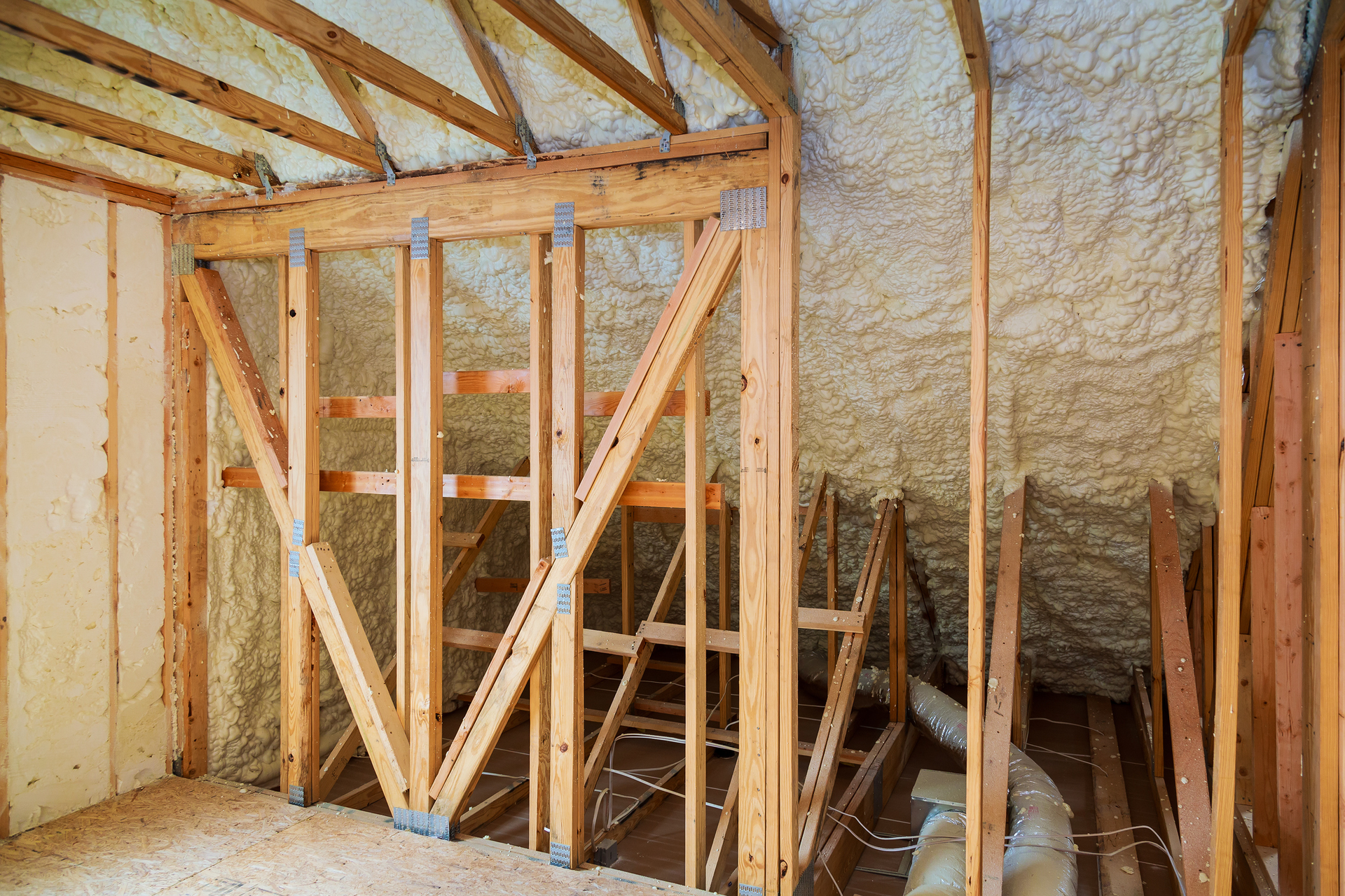 A room in a house under construction with wooden beams and insulation.