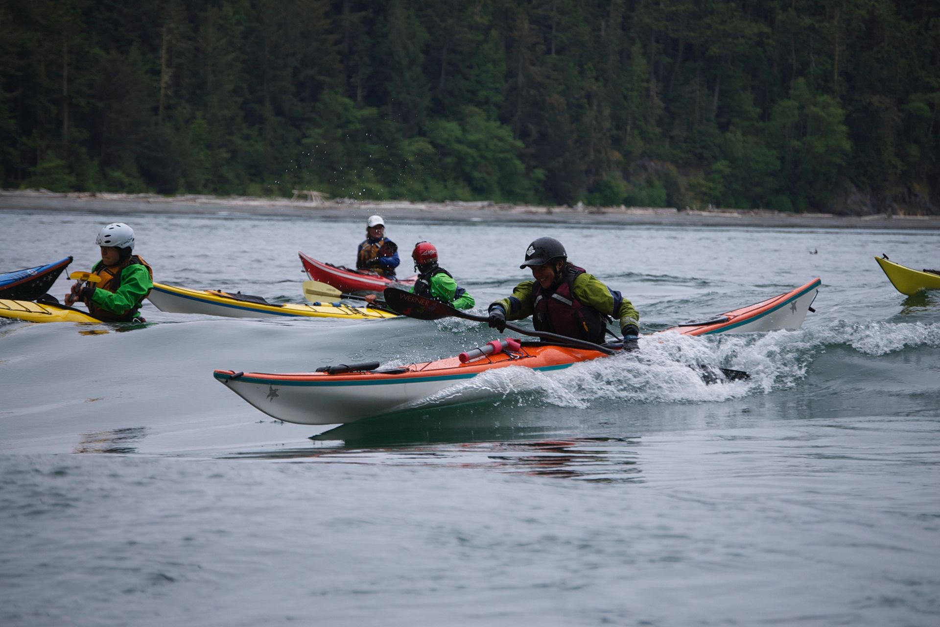 A group of people kayaking with helmets and life jackets
