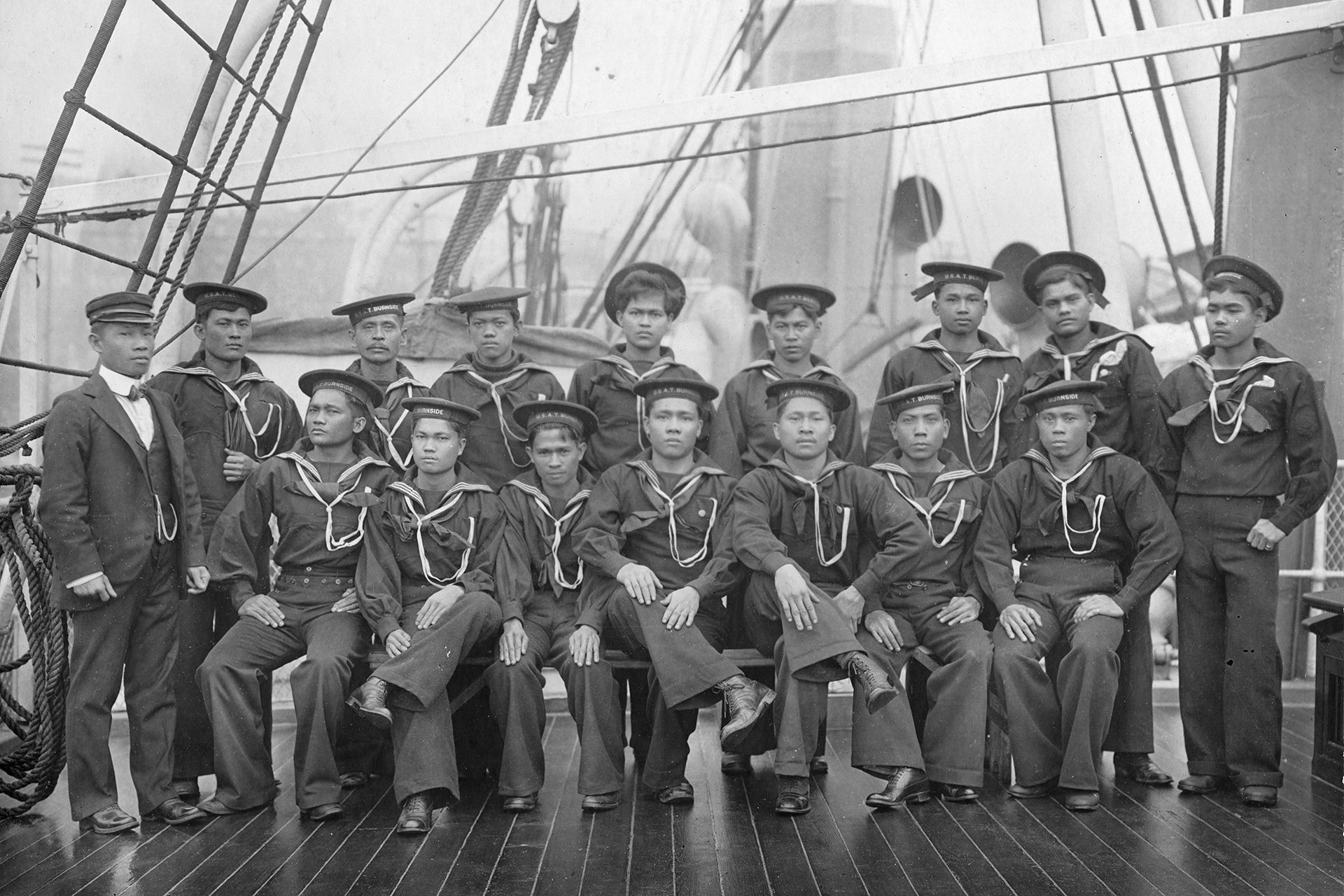 A group of sailors are posing for a picture on the deck of a ship.