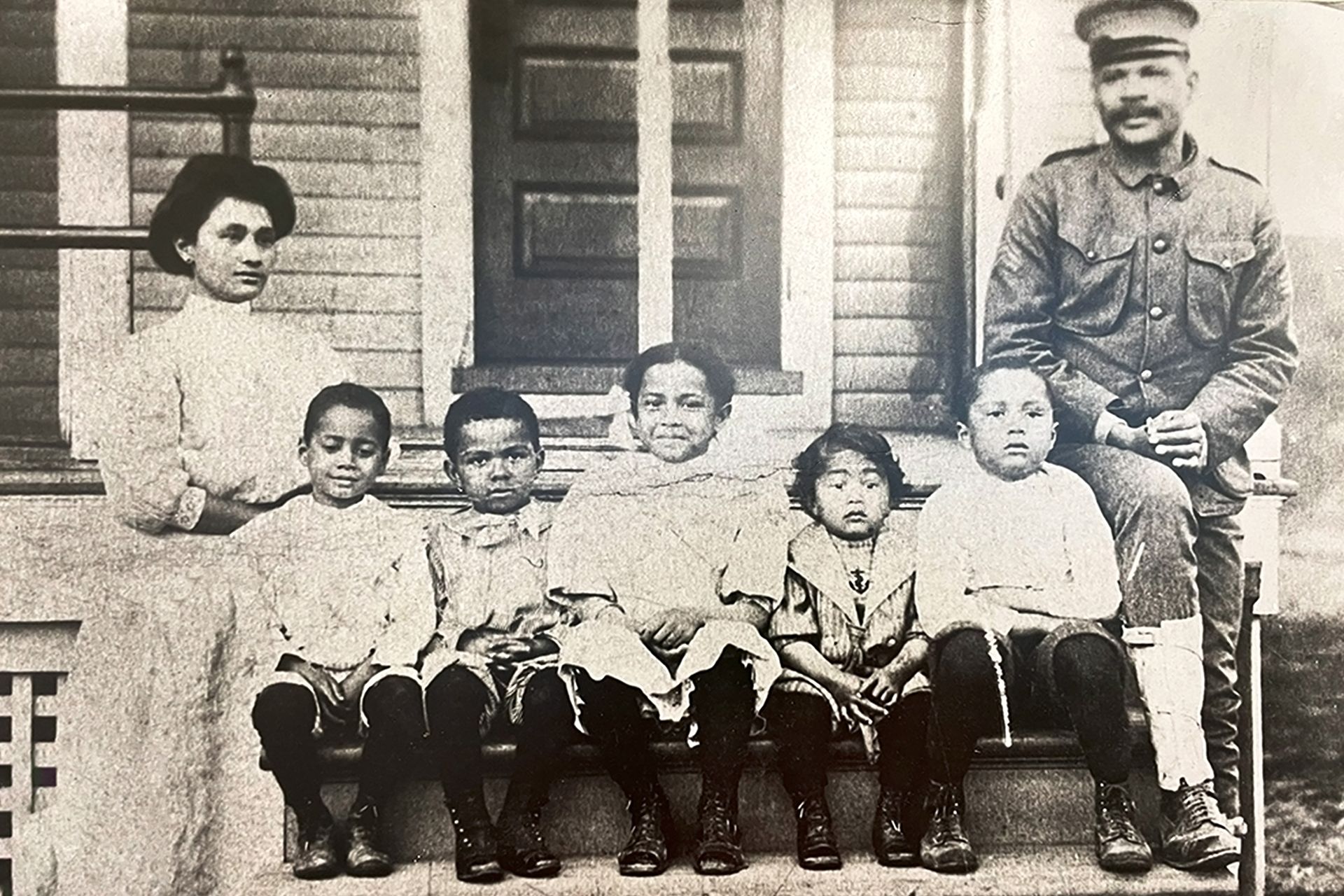 A black and white photo of a family posing for a picture on their front porch