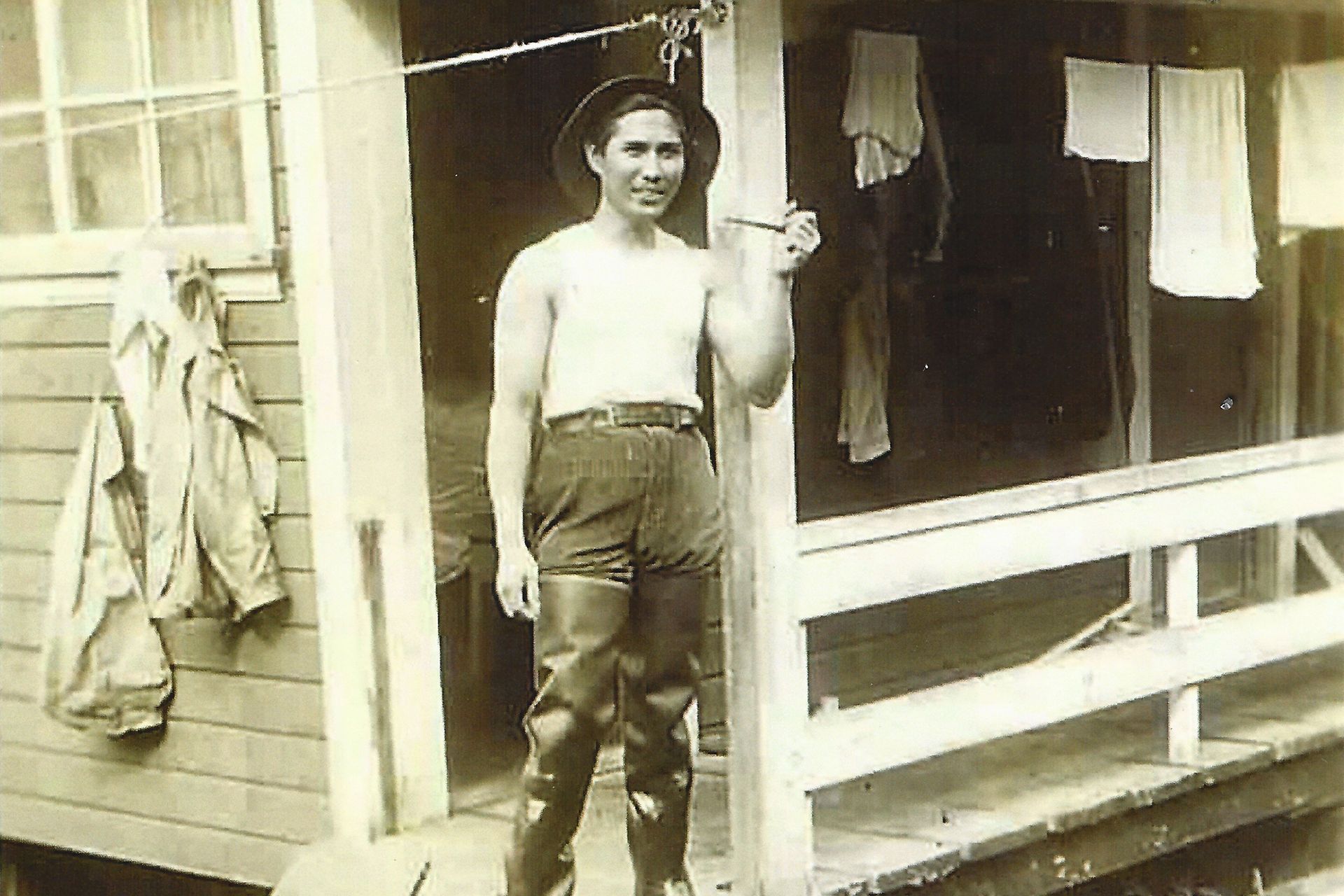 A black-and-white photo of a strawberry farmer standing outside his house.