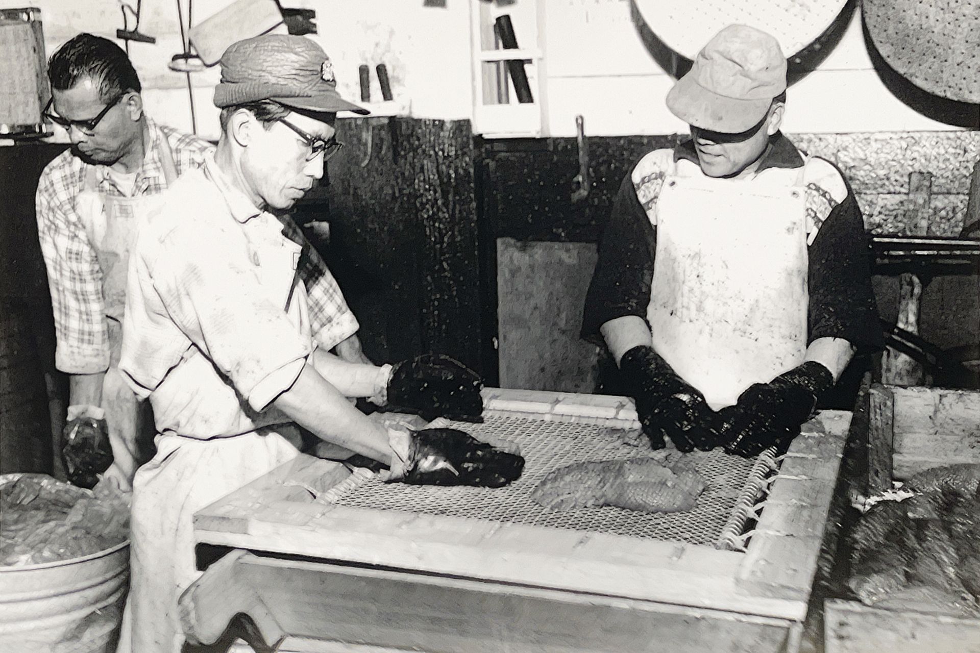 A black and white photo of three men working in a kitchen